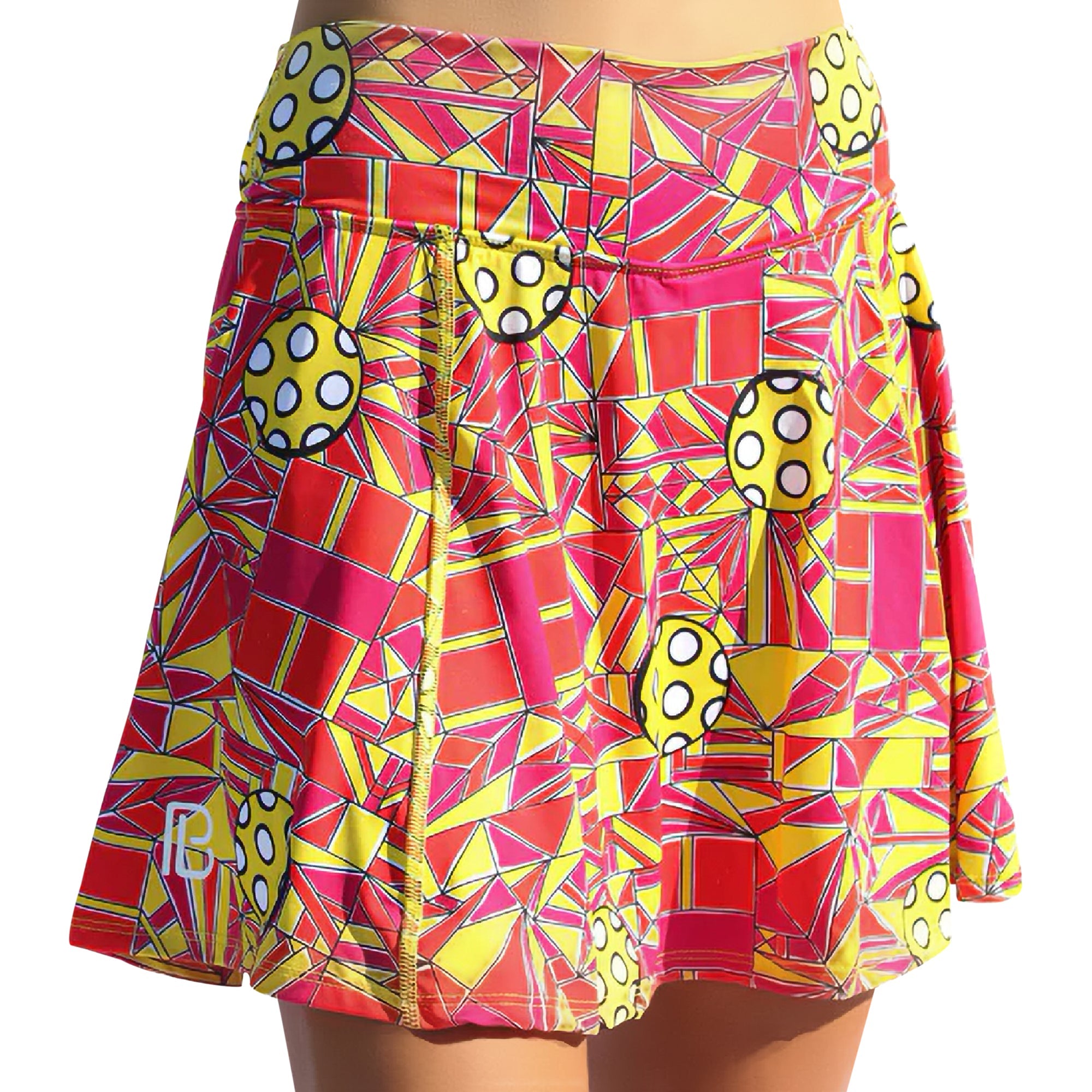 Angled shot of a vibrant red and yellow geometric A-line skort by Pickleball Bella, featuring yellow pickleball-like circles and a white PB logo.