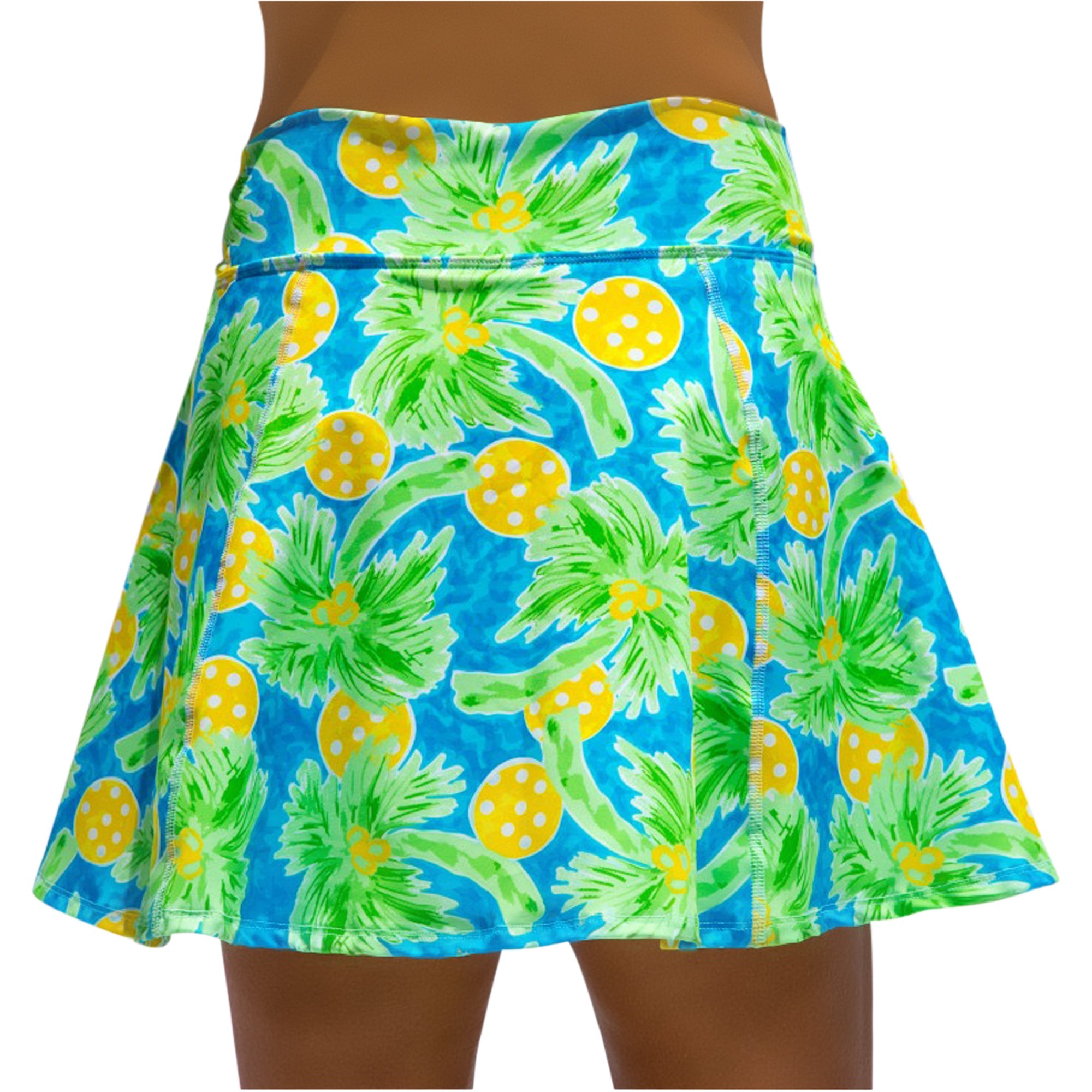 Blue, green, and yellow A-line skort by Pickleball Bella, featuring a palm tree and polka dot print, worn by a model.