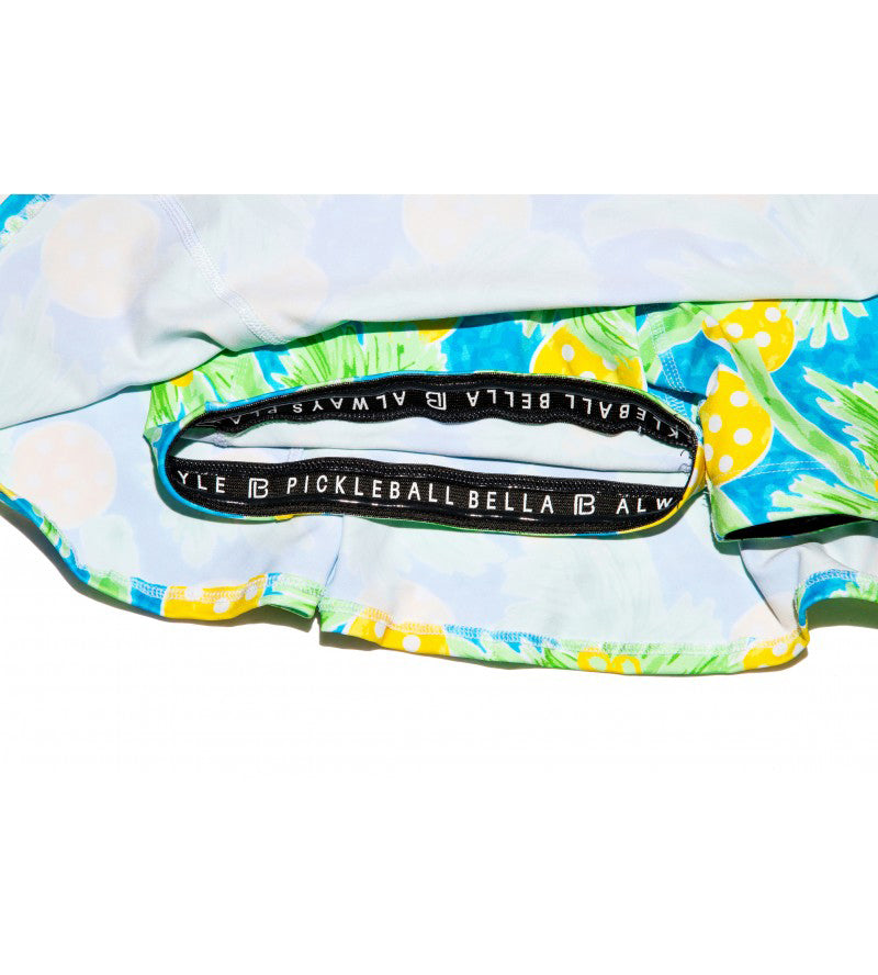 Multi-color A-line skort by Pickleball Bella with a palm and polka dot print and black logo elastic waistband.