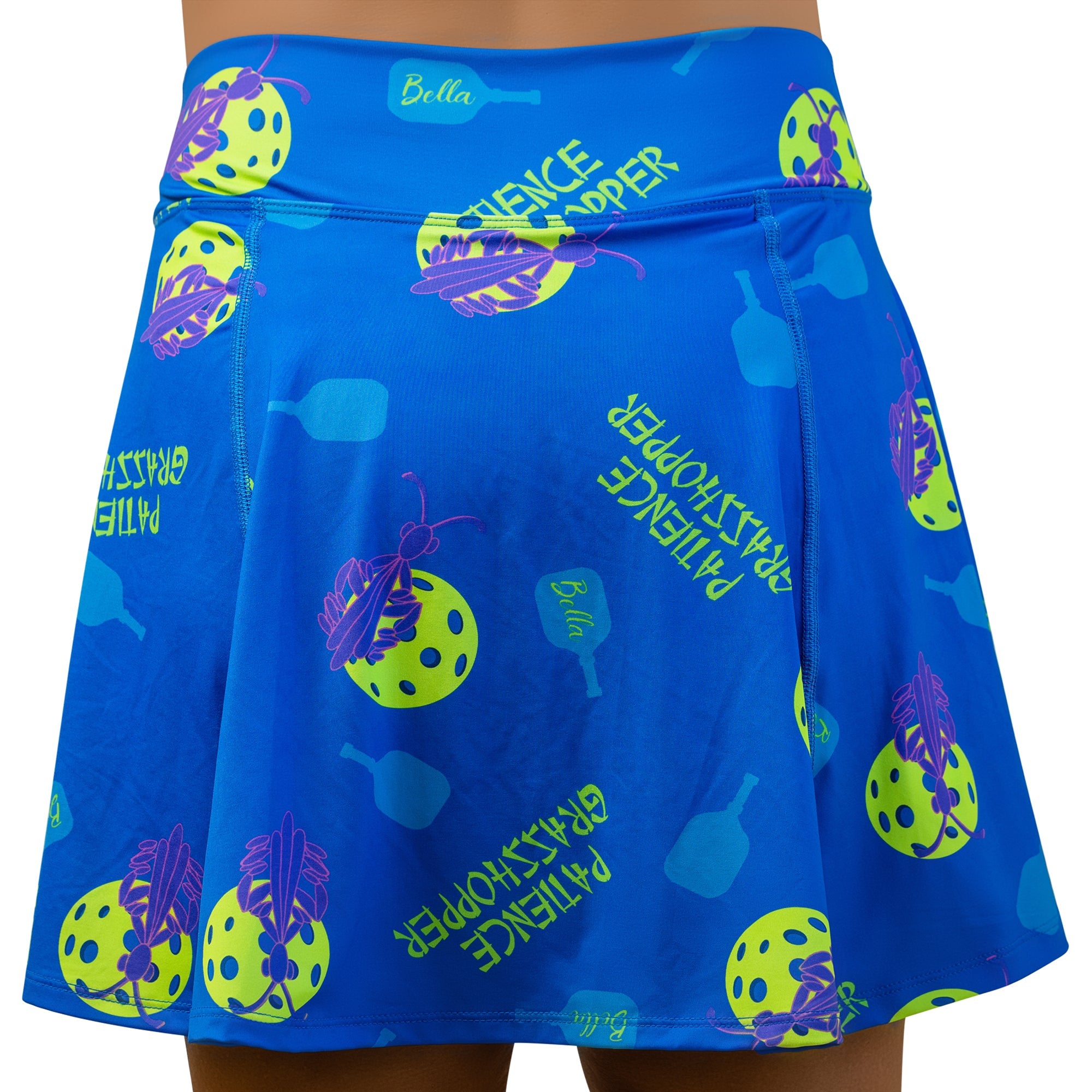 Blue A-line skort by Pickleball Bella featuring yellow pickleball balls, purple grasshoppers, and 'Patience Grasshopper' text.