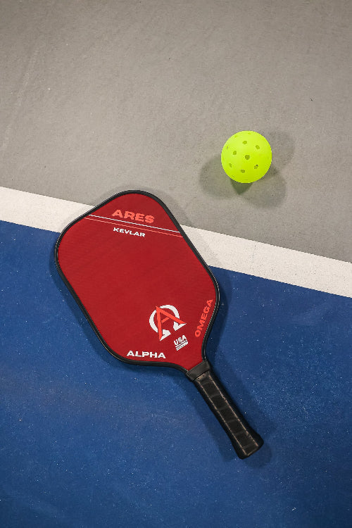 Pickleball paddle and ball on a court.