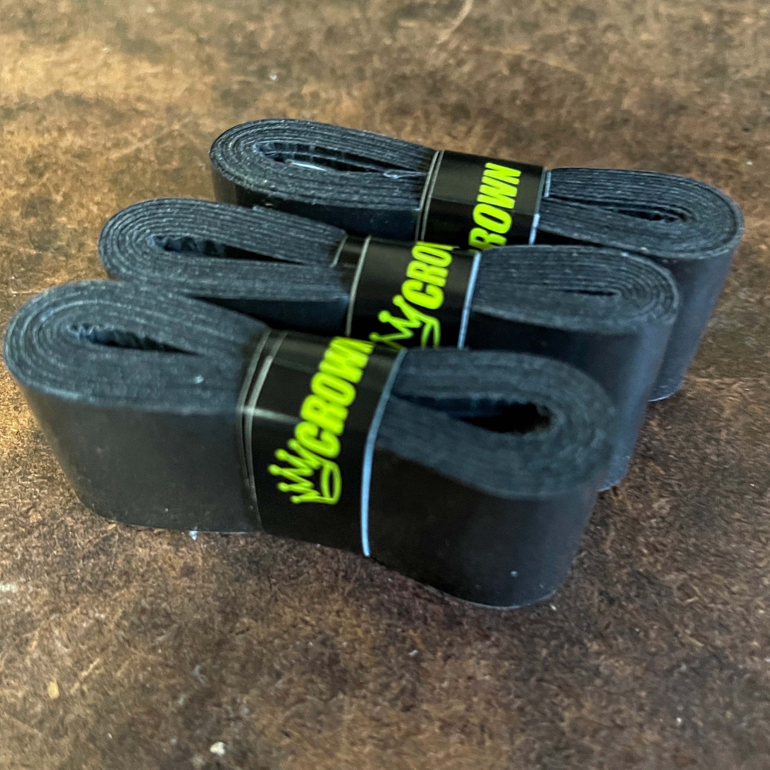 Three rolls of black athletic tape wrapped with "Crown" label on a brown surface.