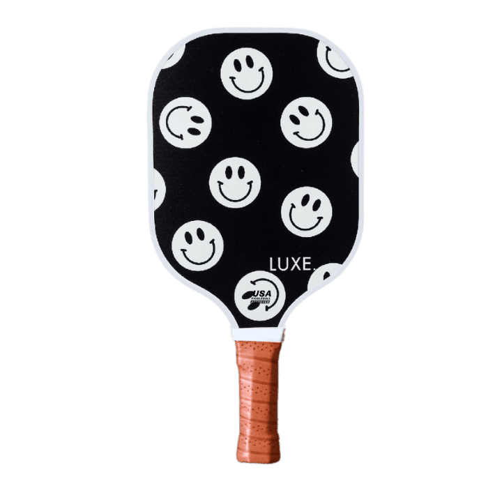 Pickleball paddle with black background, white smiley faces, brown handle.