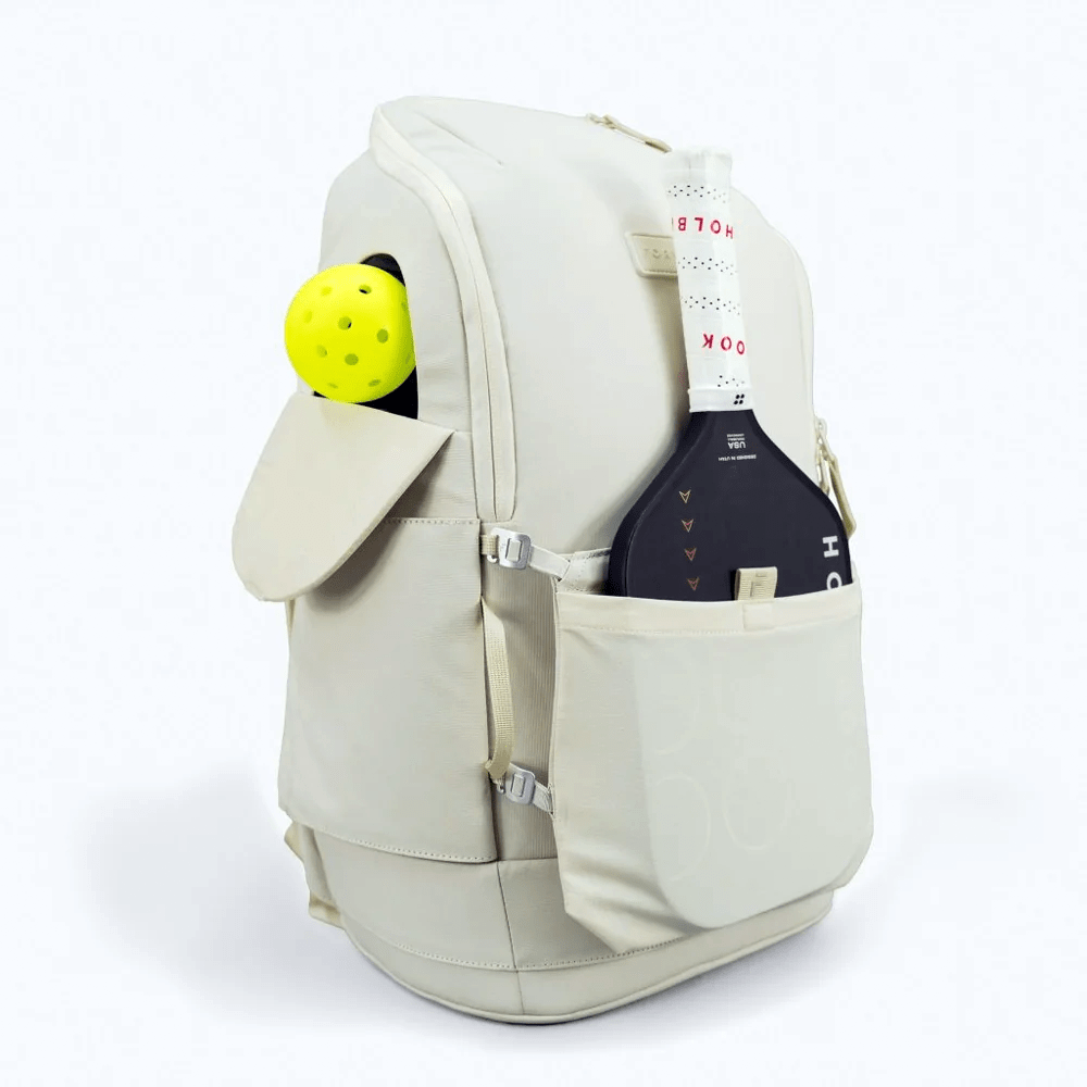 Light beige fabric pickleball backpack by FORWRD, holding a yellow pickleball and a black paddle.