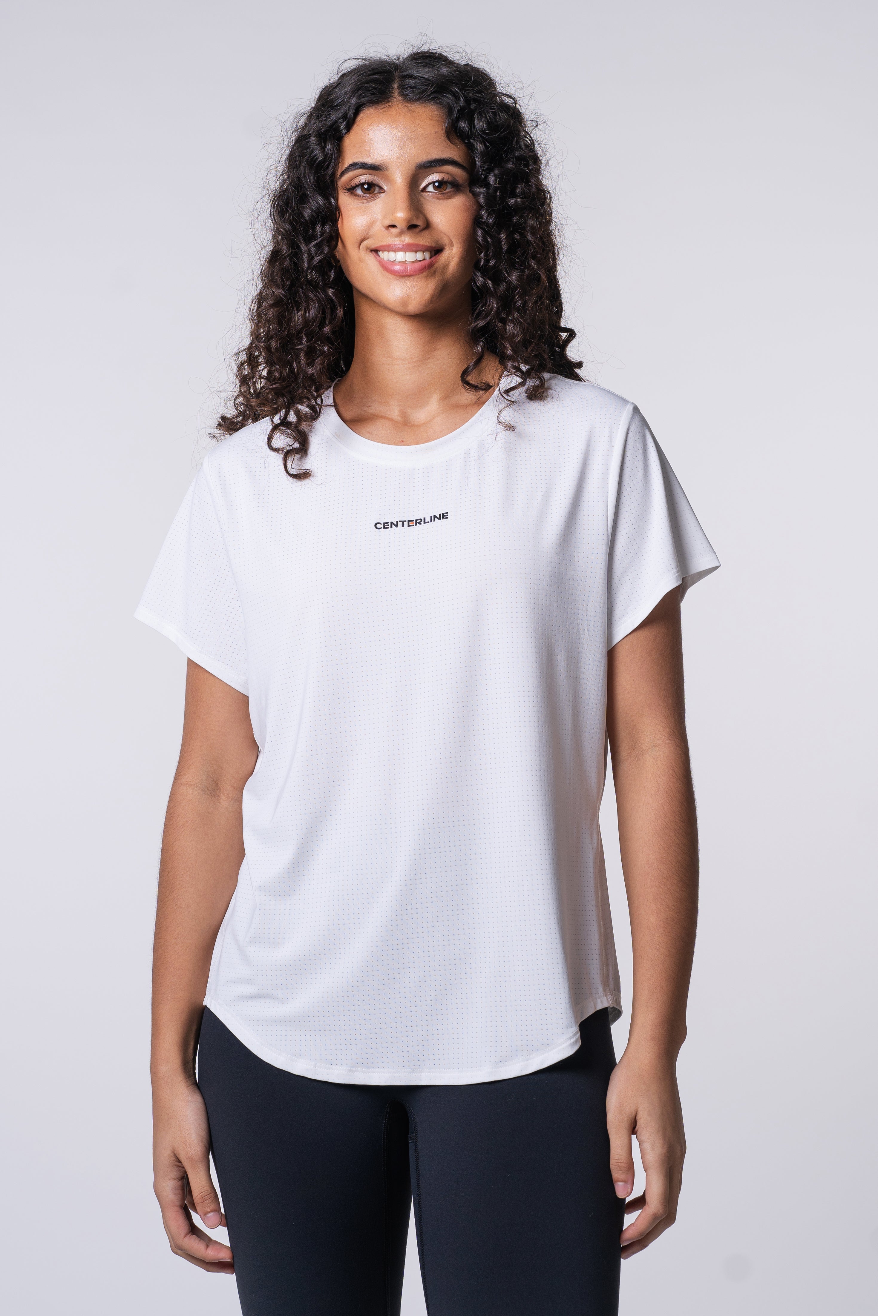 A woman in a white, short-sleeved, ventilated shirt with black leggings.