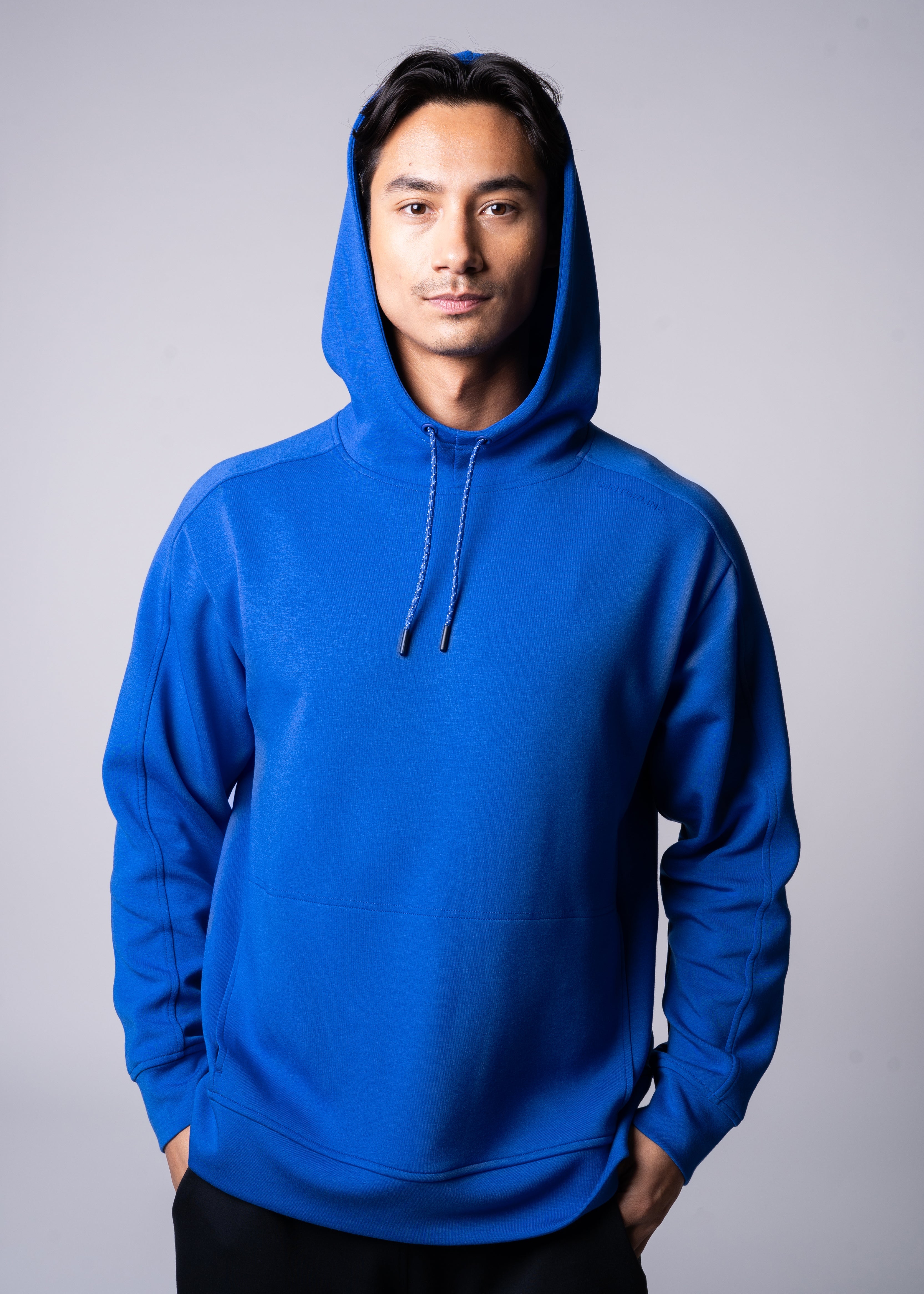Man in blue hoodie with hands in pockets.