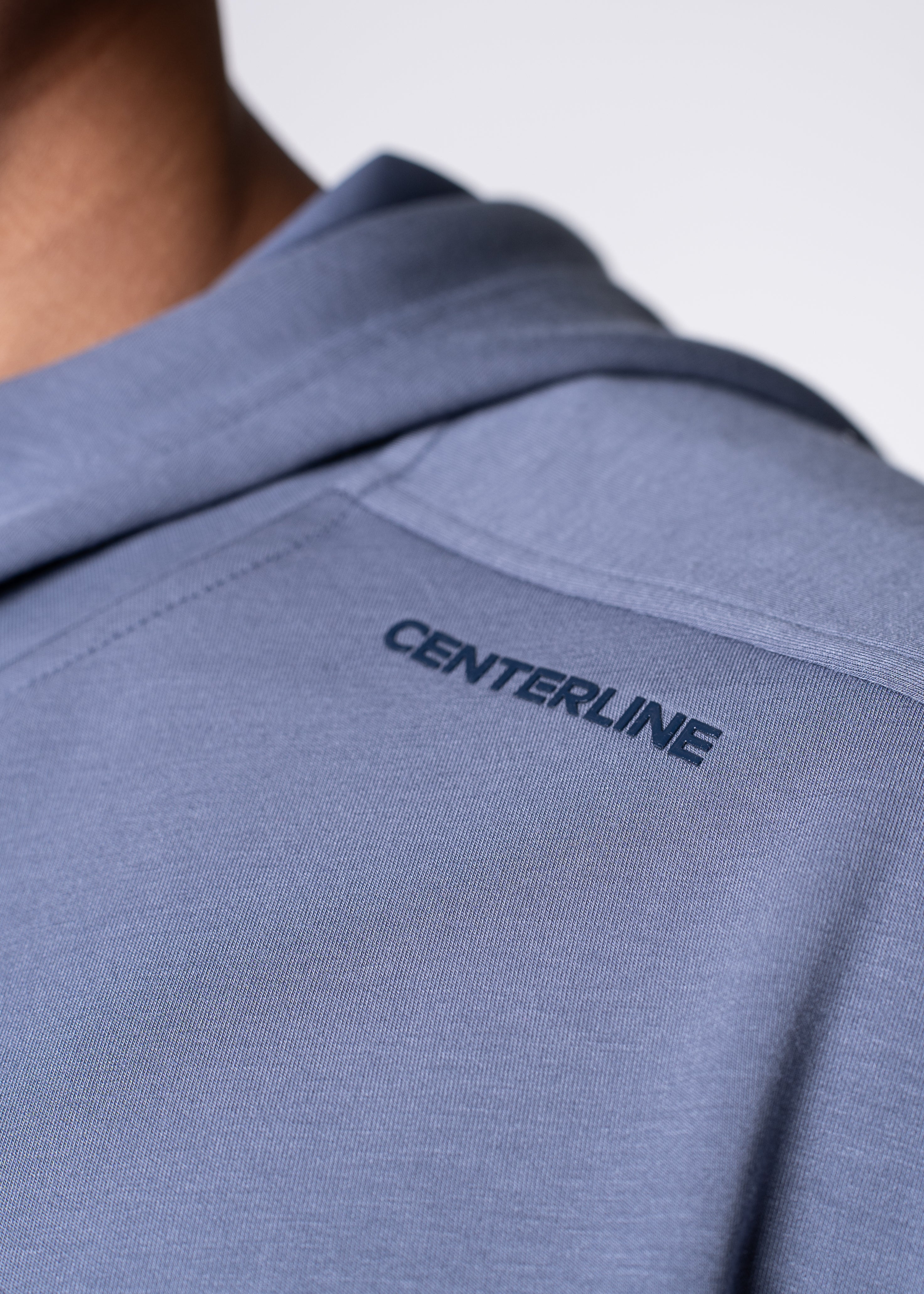 Close-up of a gray hoodie with the word "CENTERLINE" printed on the upper back.