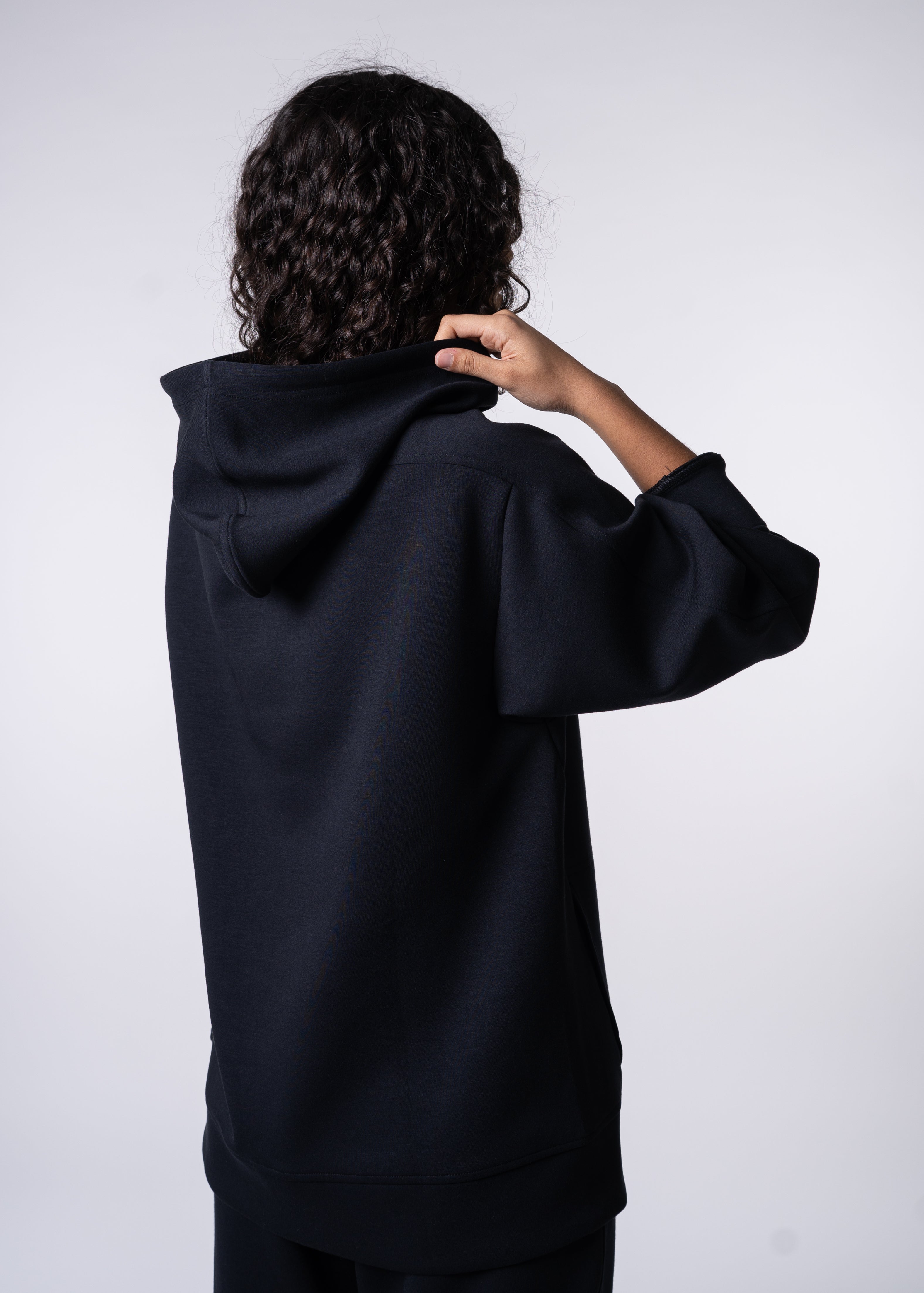 Person wearing a black hoodie with curly hair, from behind.