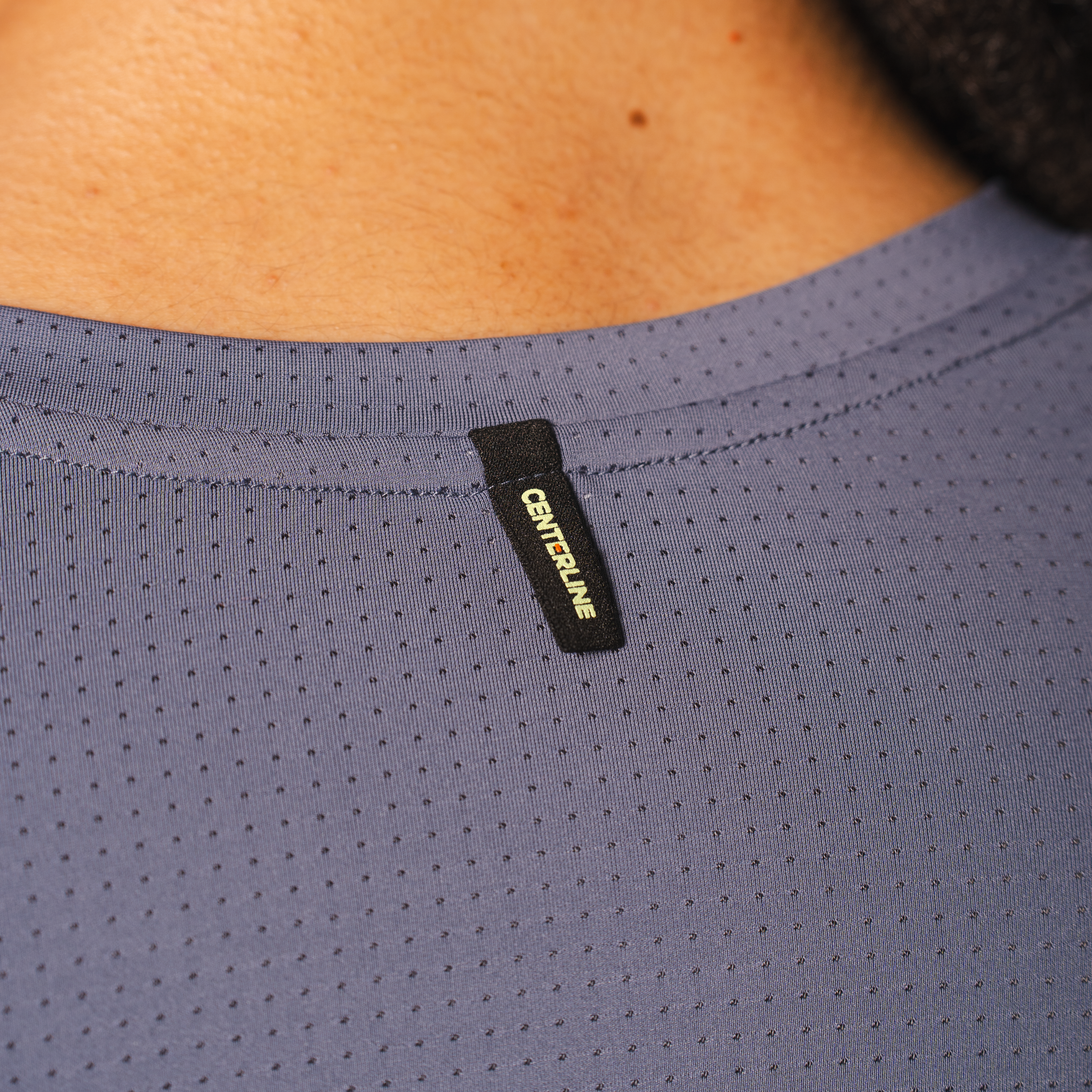 Close-up of a gray, perforated athletic shirt with a black "CENTERLINE" tag.
