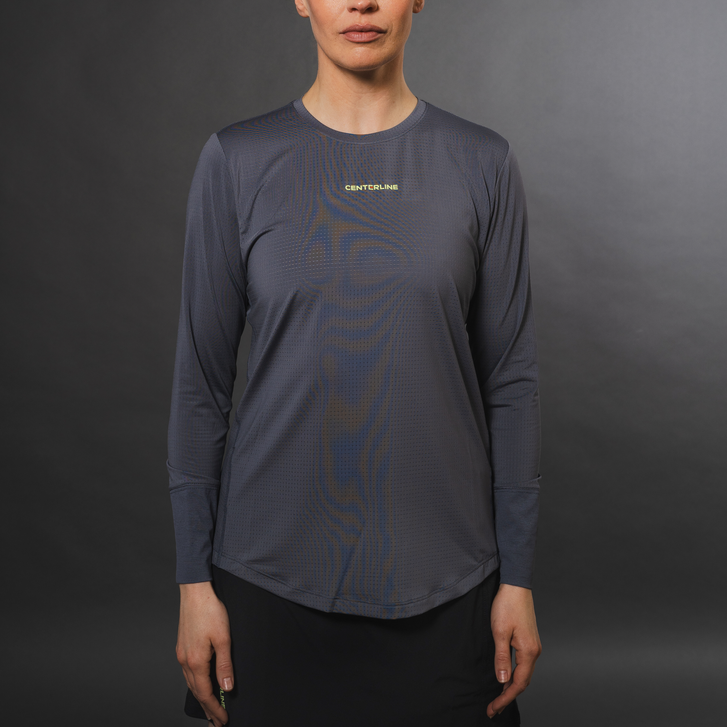 Gray long-sleeved shirt, black skirt, neutral background.