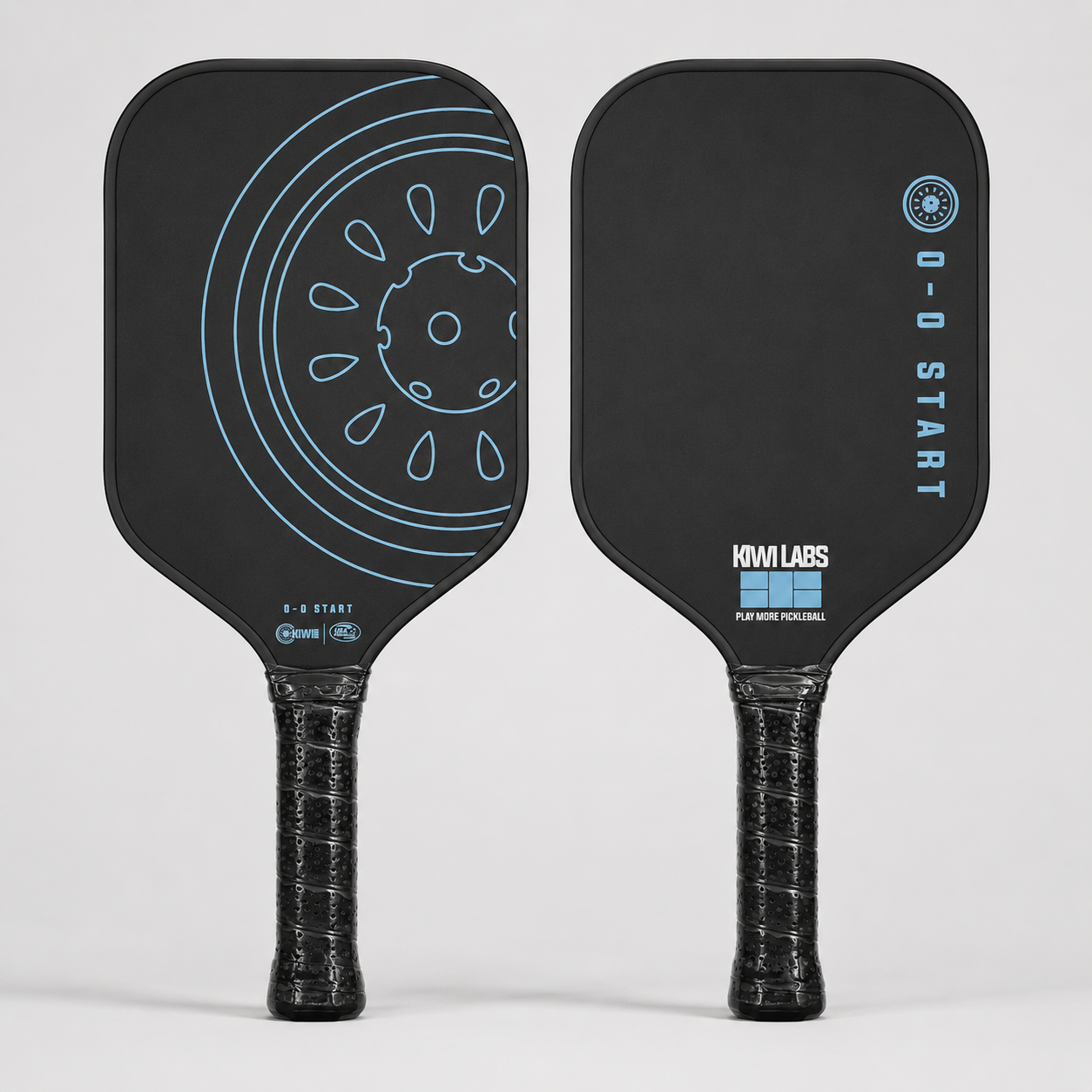 Front and back views of a black carbon fiber pickleball paddle by Kiwi Labs Pickleball, with light blue graphics including a wheel and '0-0 START' text.