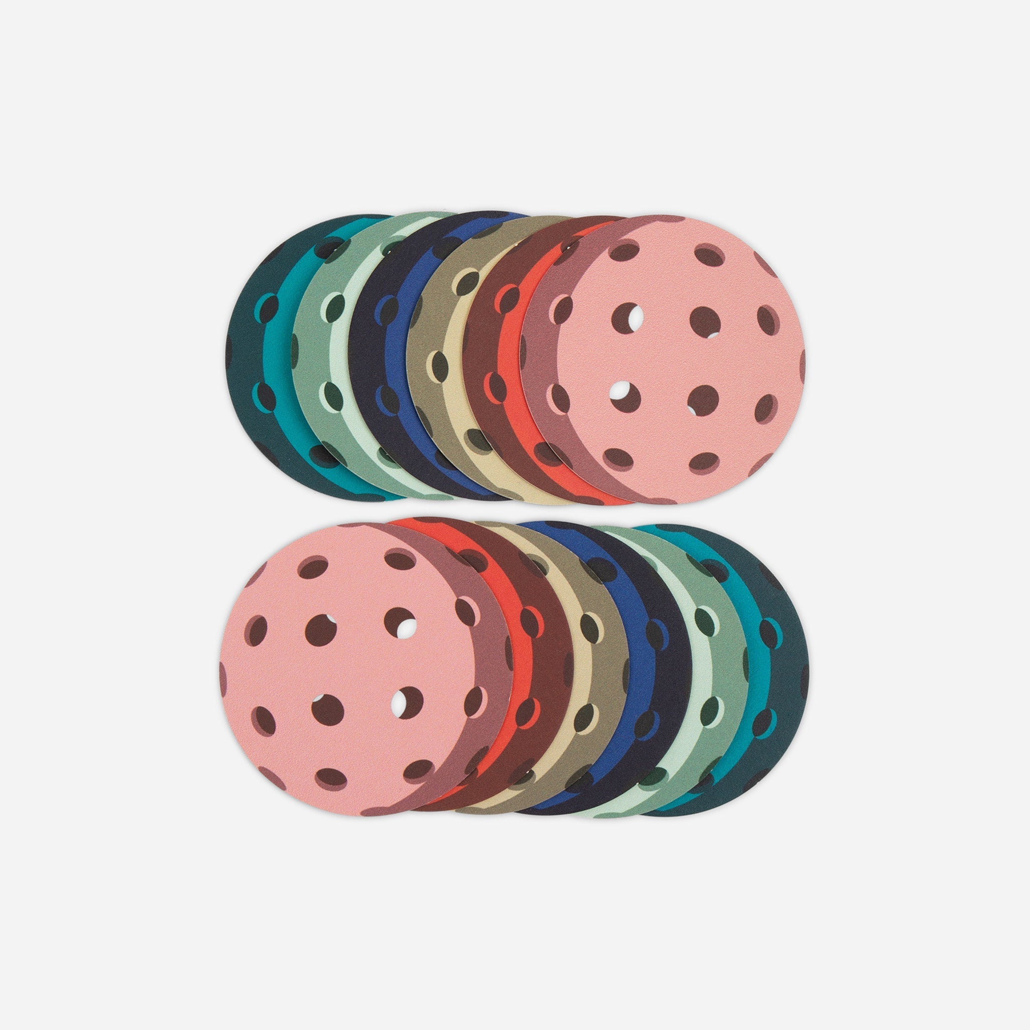 Multiple colorful round mats with holes stacked in two rows on a white background.