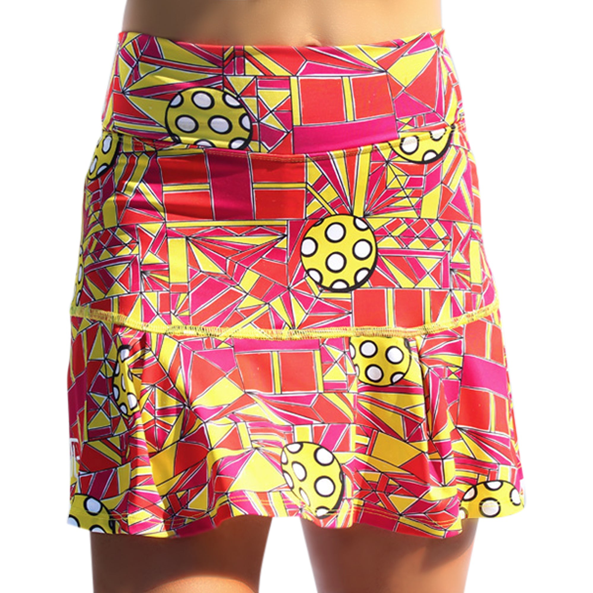 Red, yellow, and pink geometric pleat skort by Pickleball Bella, with pickleball graphics and a pleated hem.
