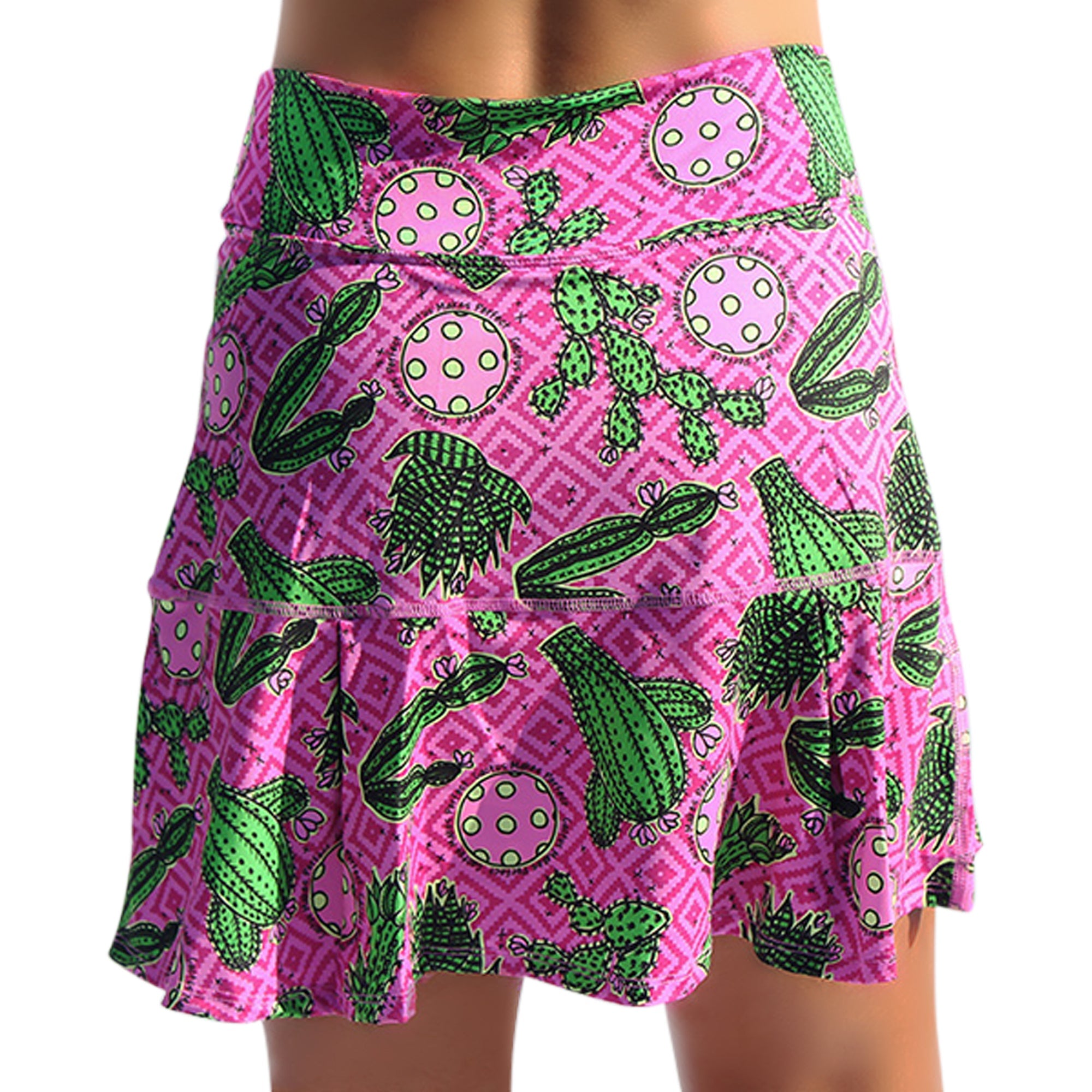 Pink drop pleat skort by Pickleball Bella with green cactus and polka dot pattern on a geometric background.