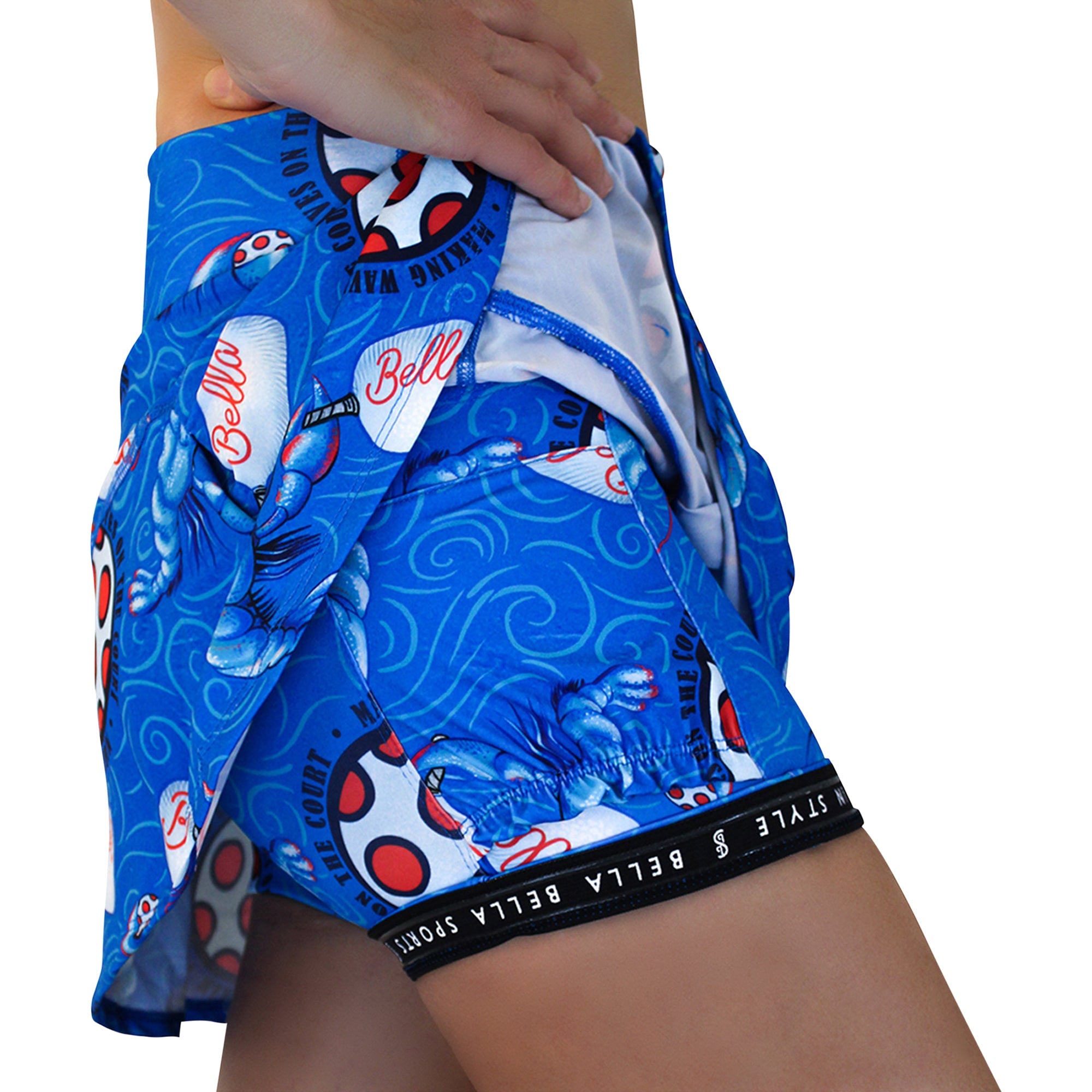 Blue drop pleat skort by Pickleball Bella, featuring a lobster monster and 'On The Court' pattern with a black 'Bella Sports' waistband.