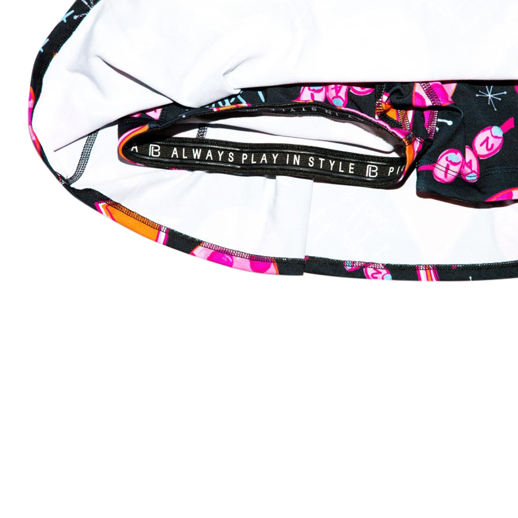 A black pleat skort by Pickleball Bella, featuring pink martini glass print, built-in shorts, and an "ALWAYS PLAY IN STYLE" elastic waistband.