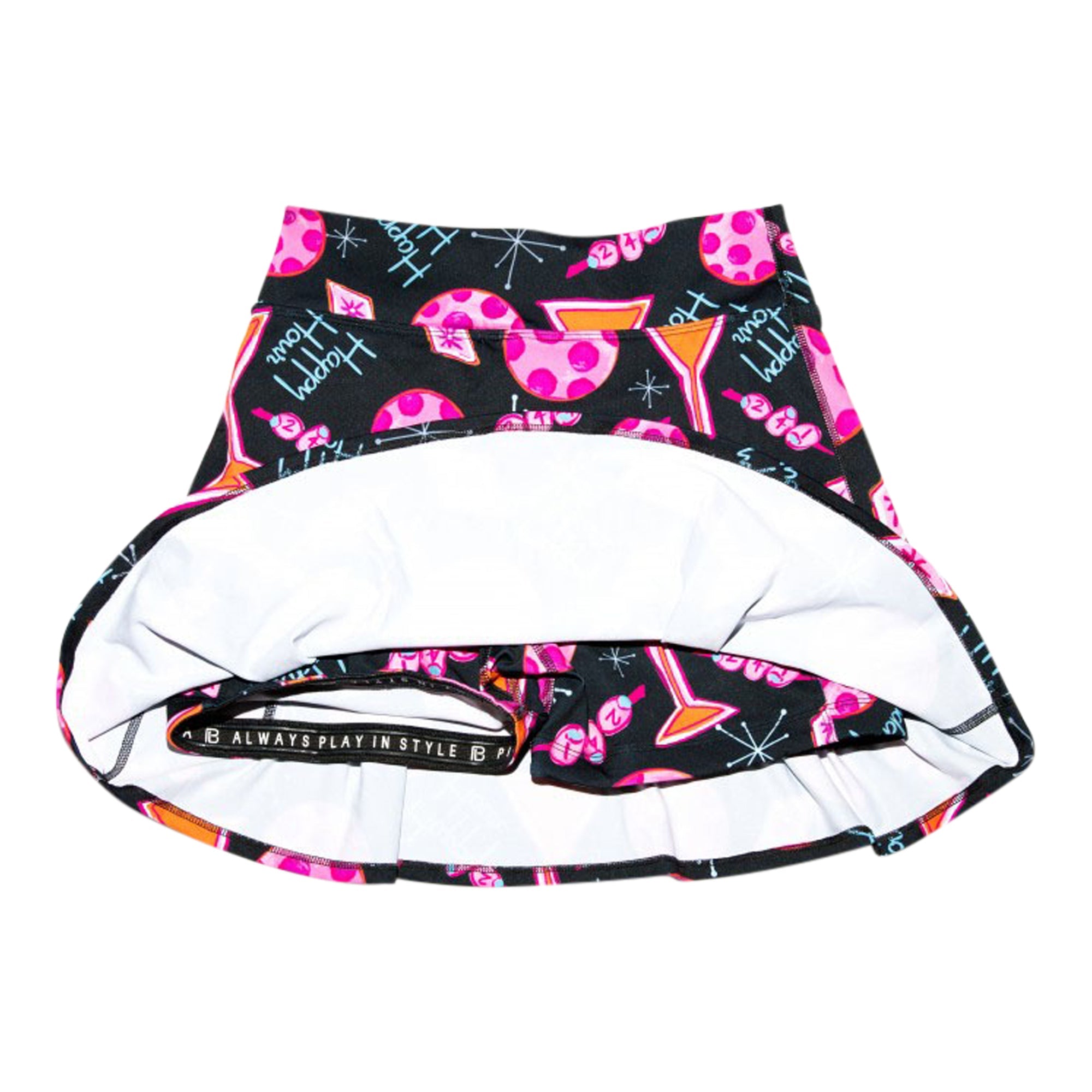 Black drop pleat skort by Pickleball Bella with "Happy Hour" stylized text, martini and pickleball graphics, revealing white undershorts with an "ALWAYS PLAY IN STYLE" waistband.