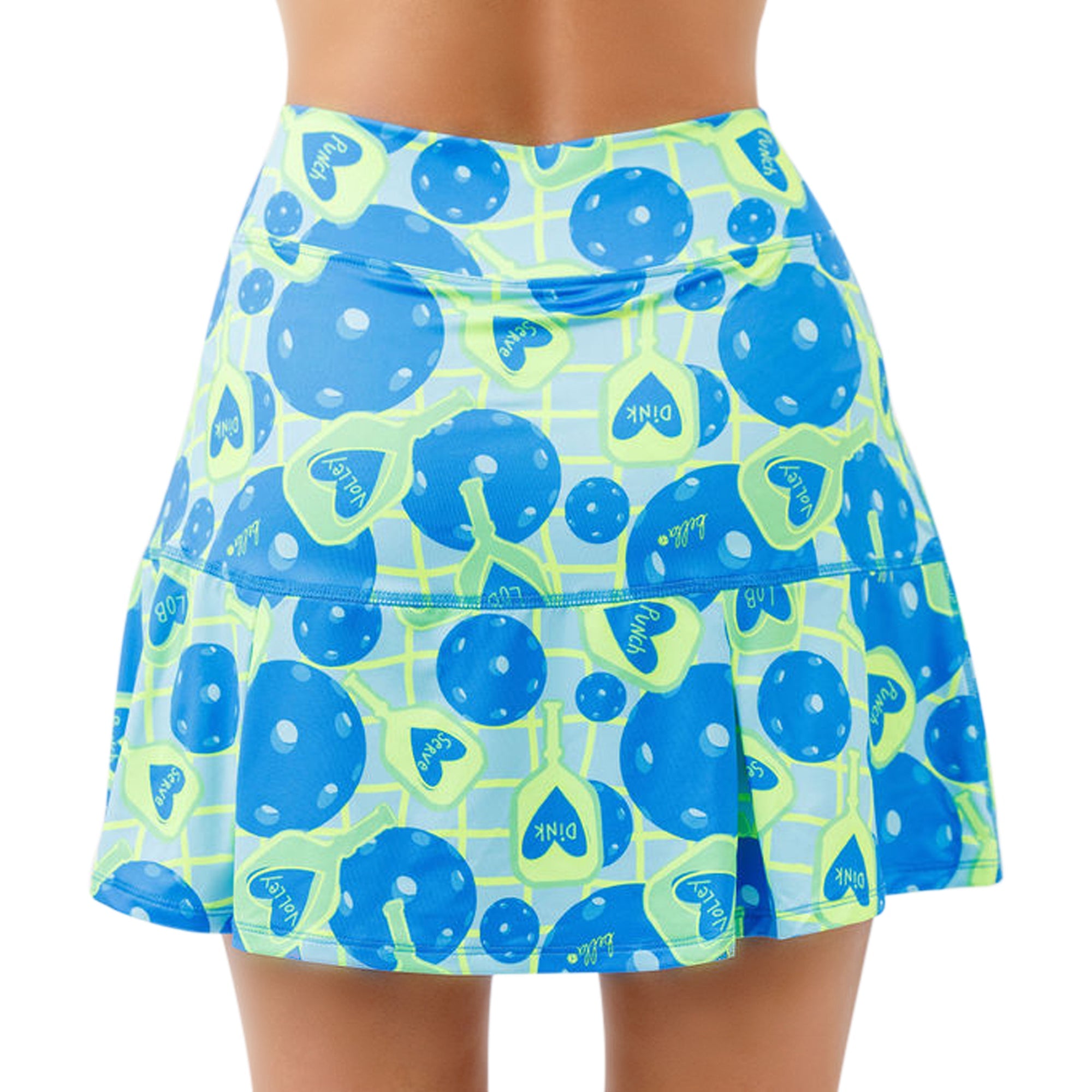 Blue and green patterned pleat skort by Pickleball Bella, featuring pickleball paddles, balls, and game terms, worn by a model.