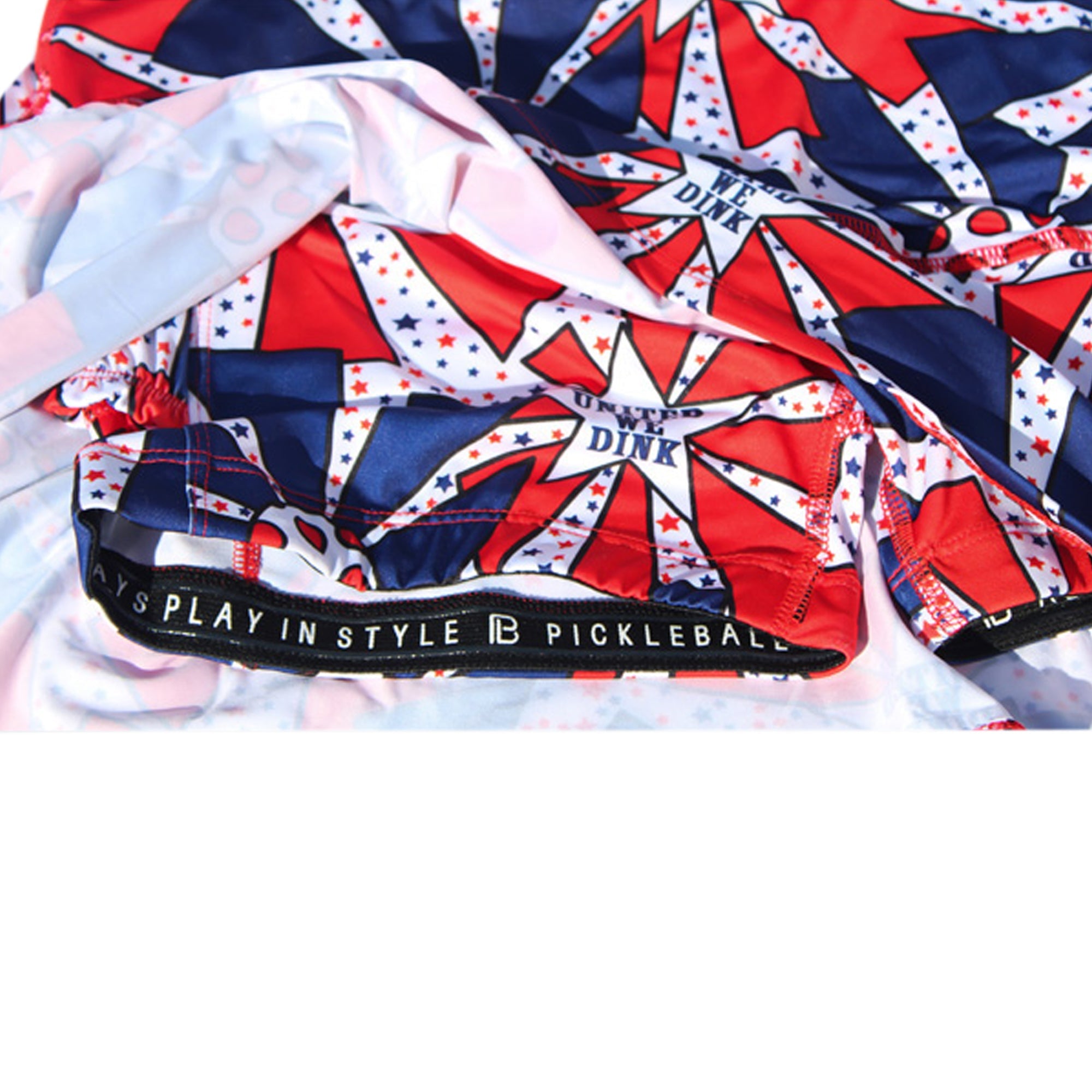 Red, white, and blue drop pleat skort by Pickleball Bella, with a "United We Dink" star pattern and "Always Play in Style" waistband.