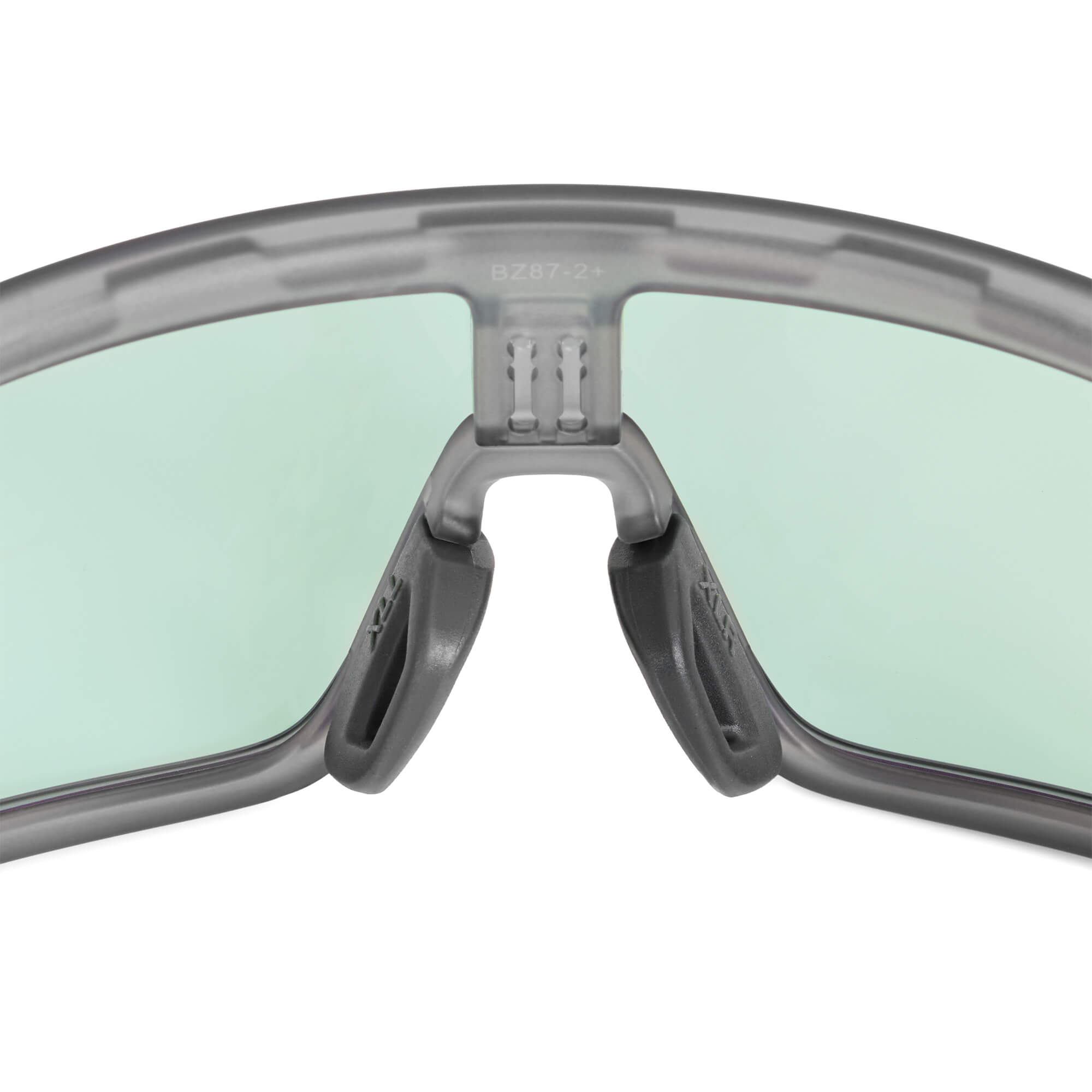 Dark gray nose pads by BRIOTI, a close-up view attached to a translucent gray eyeglass frame with light green lenses.