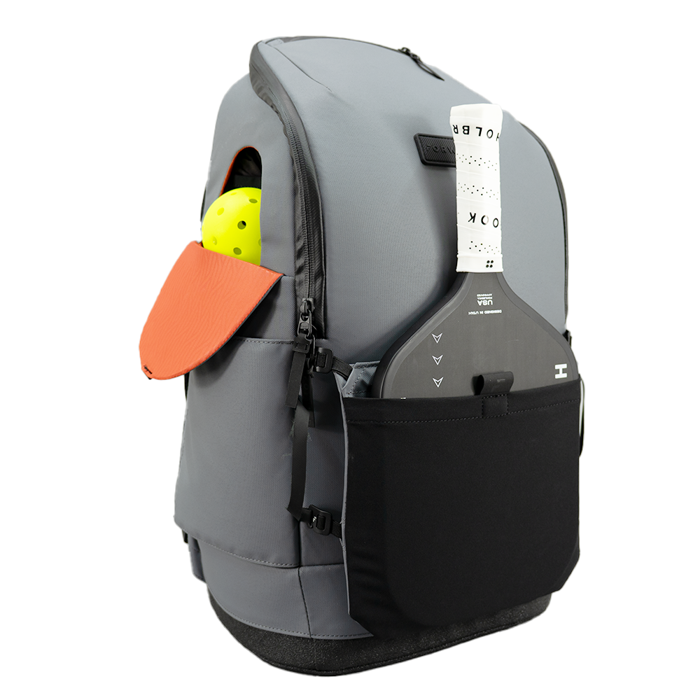 Grey pickleball backpack by FORWRD, with a yellow pickleball and black paddle in side pockets, side view.