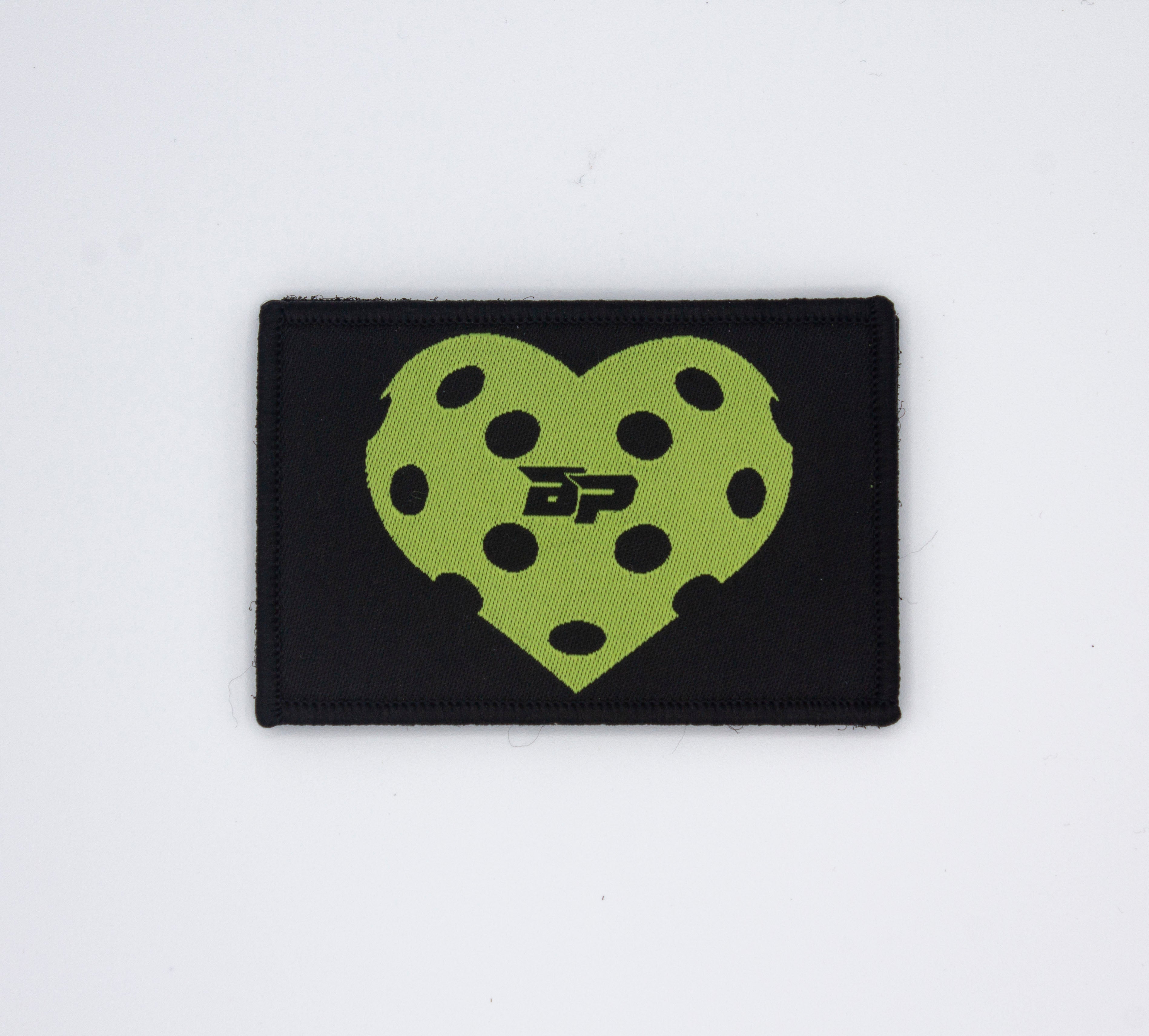 Black rectangular Velcro patch by Bodhi Performance, featuring a lime green pickleball heart design with black holes and a 'BP' logo.