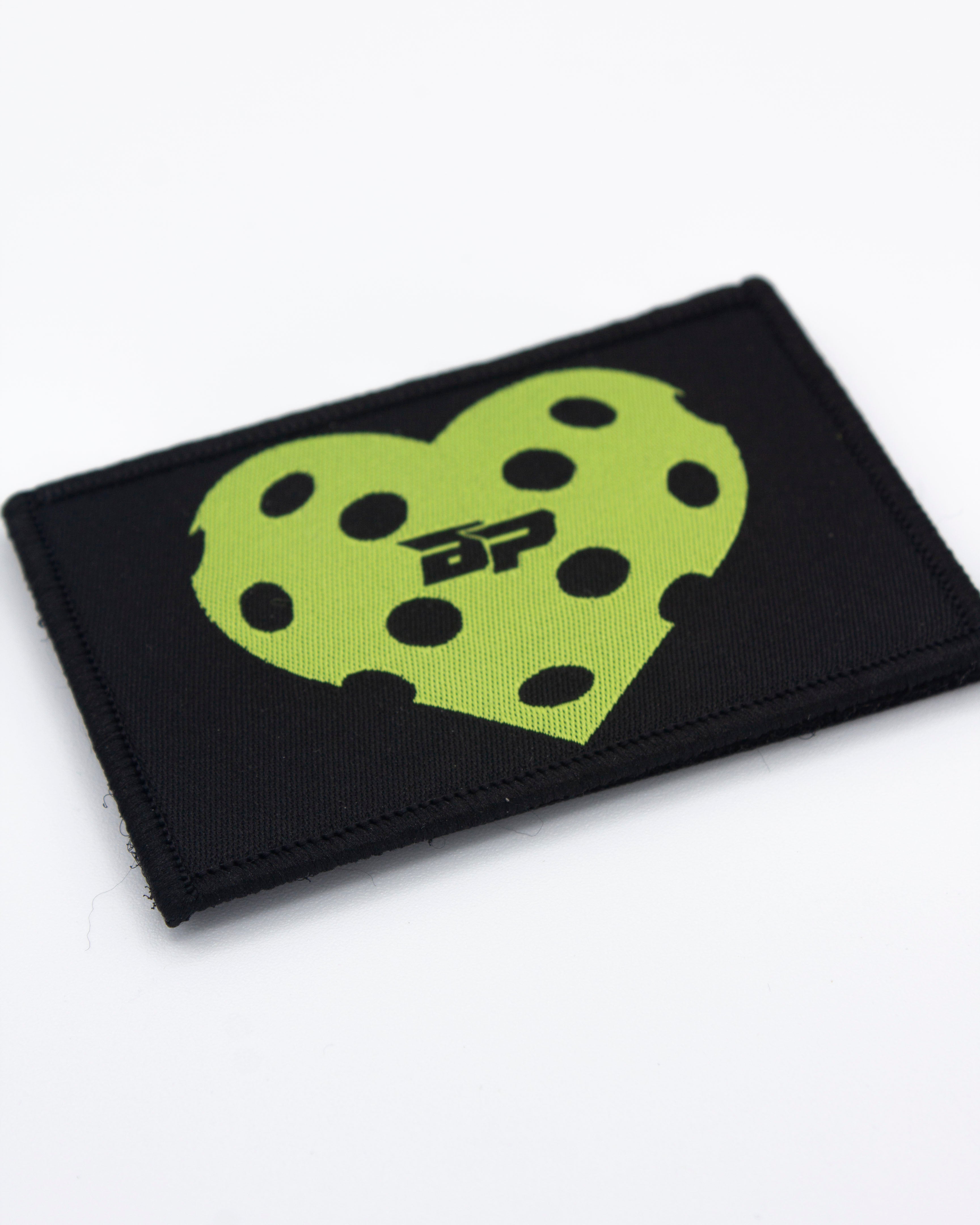 Black rectangular Velcro patch by Bodhi Performance, featuring a vibrant green heart with black polka dots and a 'BP' logo.