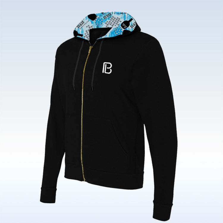 Black full-zip hoodie by Pickleball Bella with a blue and grey pickleball graffiti-patterned hood lining, gold zipper, and white B logo.