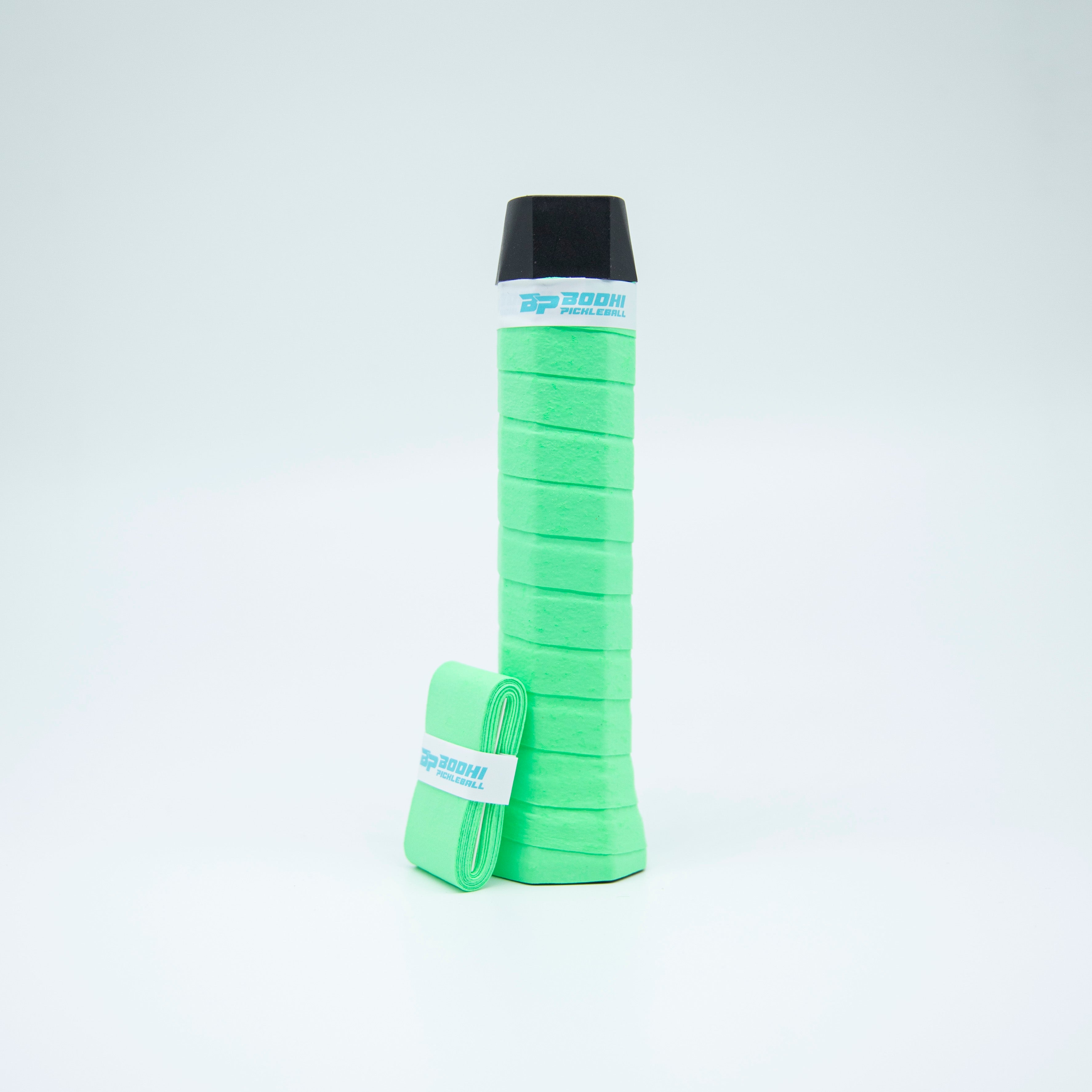 Mint-green pickleball grip and partially rolled replacement grip, black racket butt.