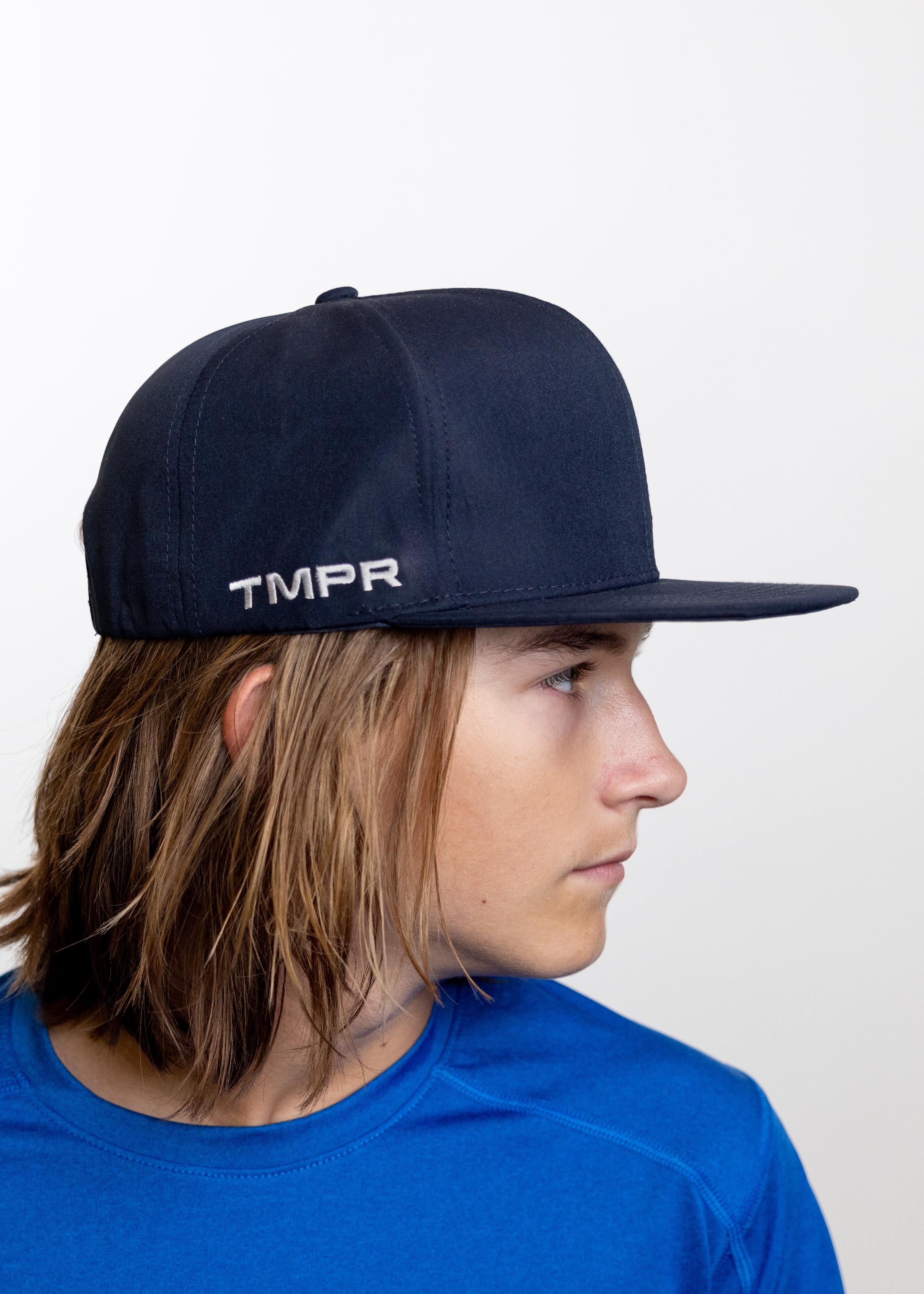 Navy blue Flat Bill Cap by TMPR Sports, featuring a white embroidered "TMPR" logo, shown in a side view.