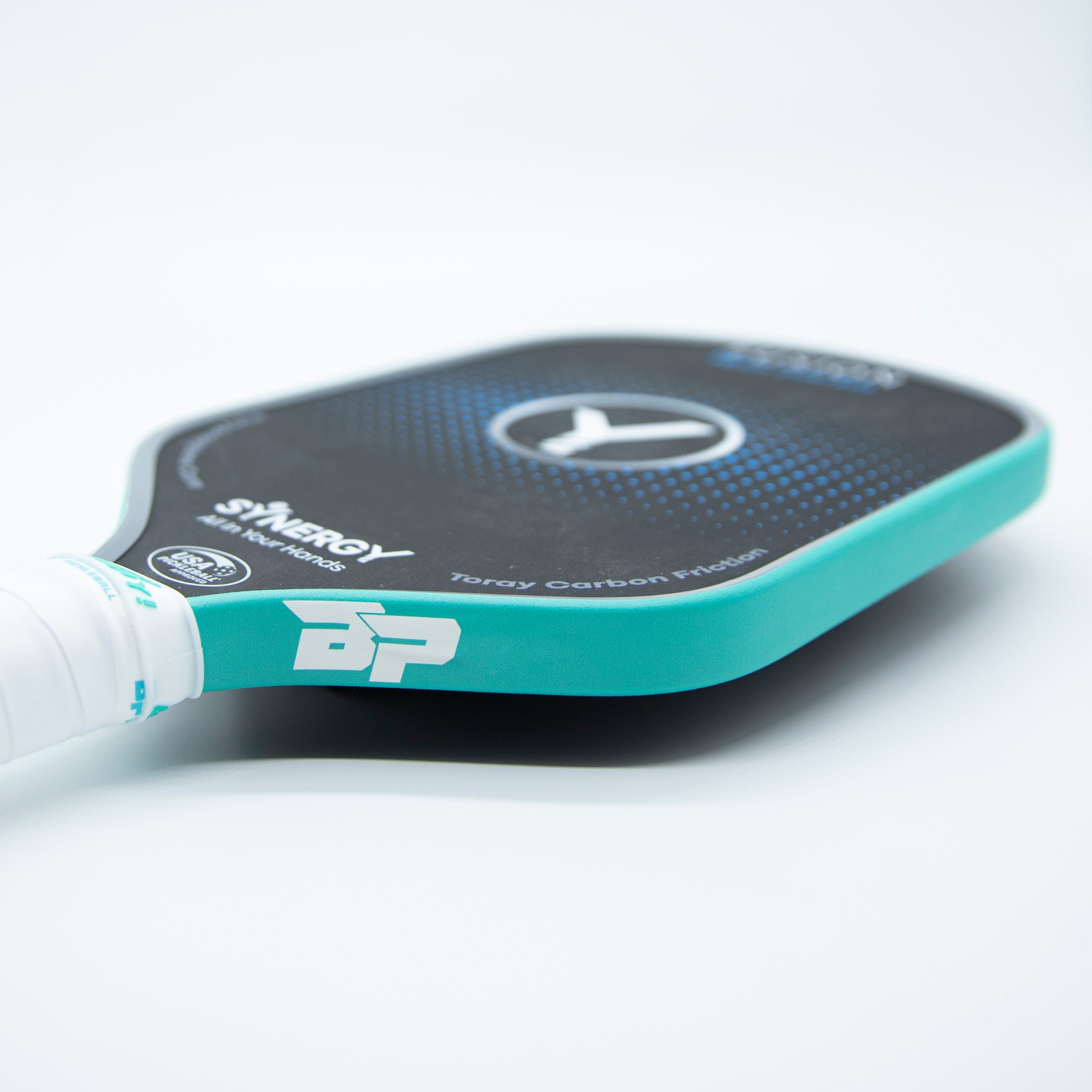 Close-up of a teal and black pickleball paddle with white grip on a white background.