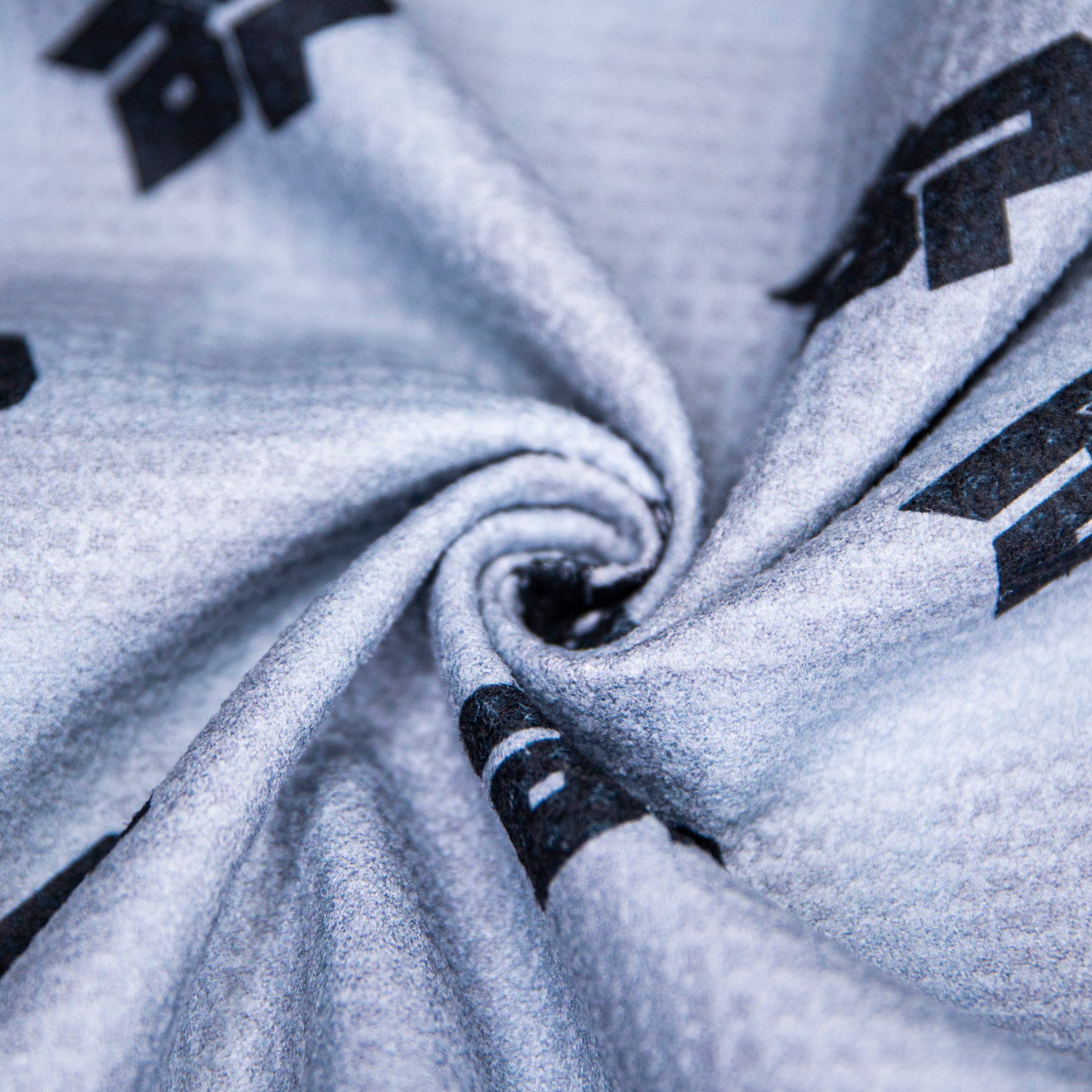Close-up of a gray fabric with a black pattern arranged in a swirl.