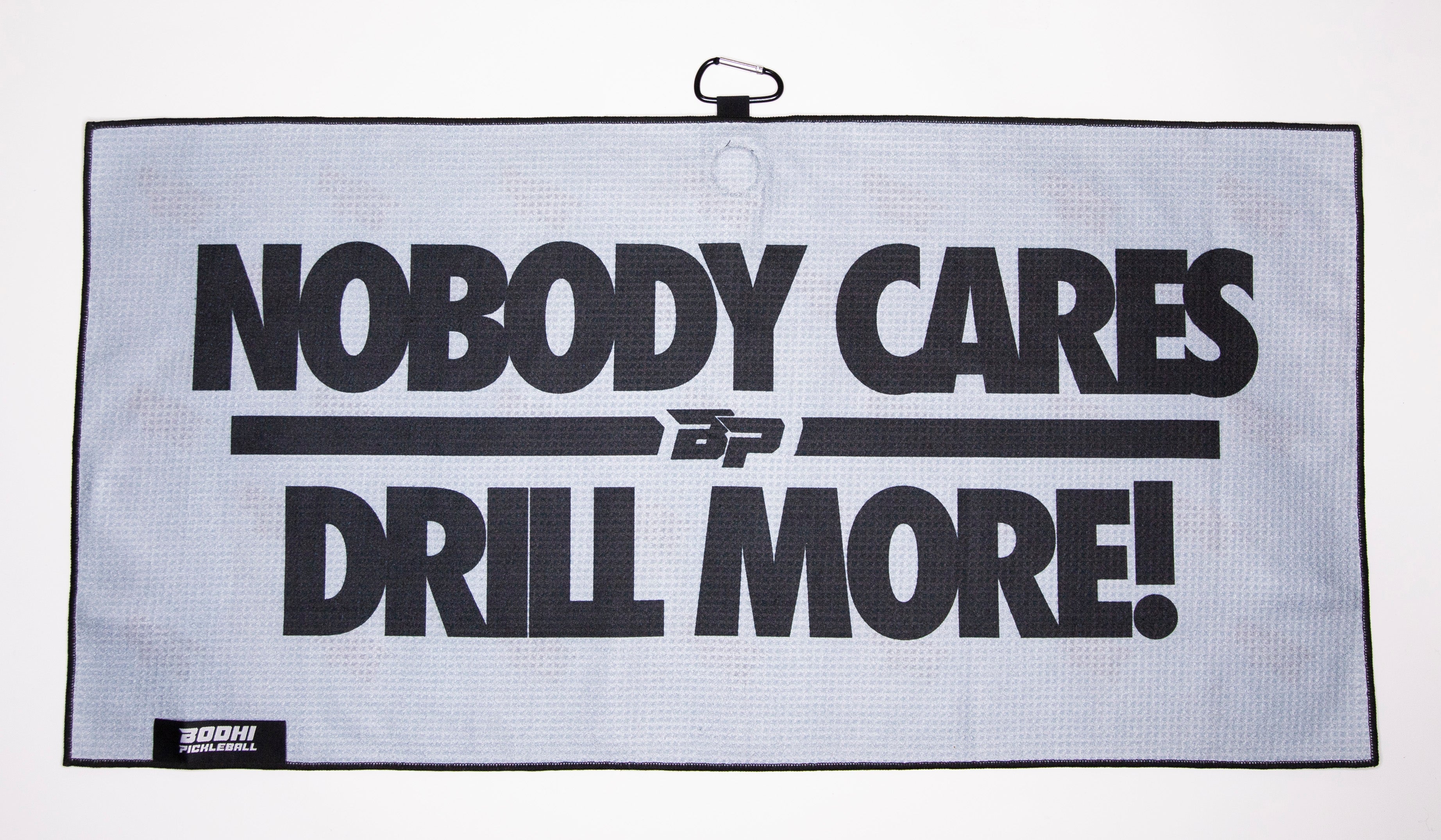 Gray towel with black text "Nobody Cares Drill More!".