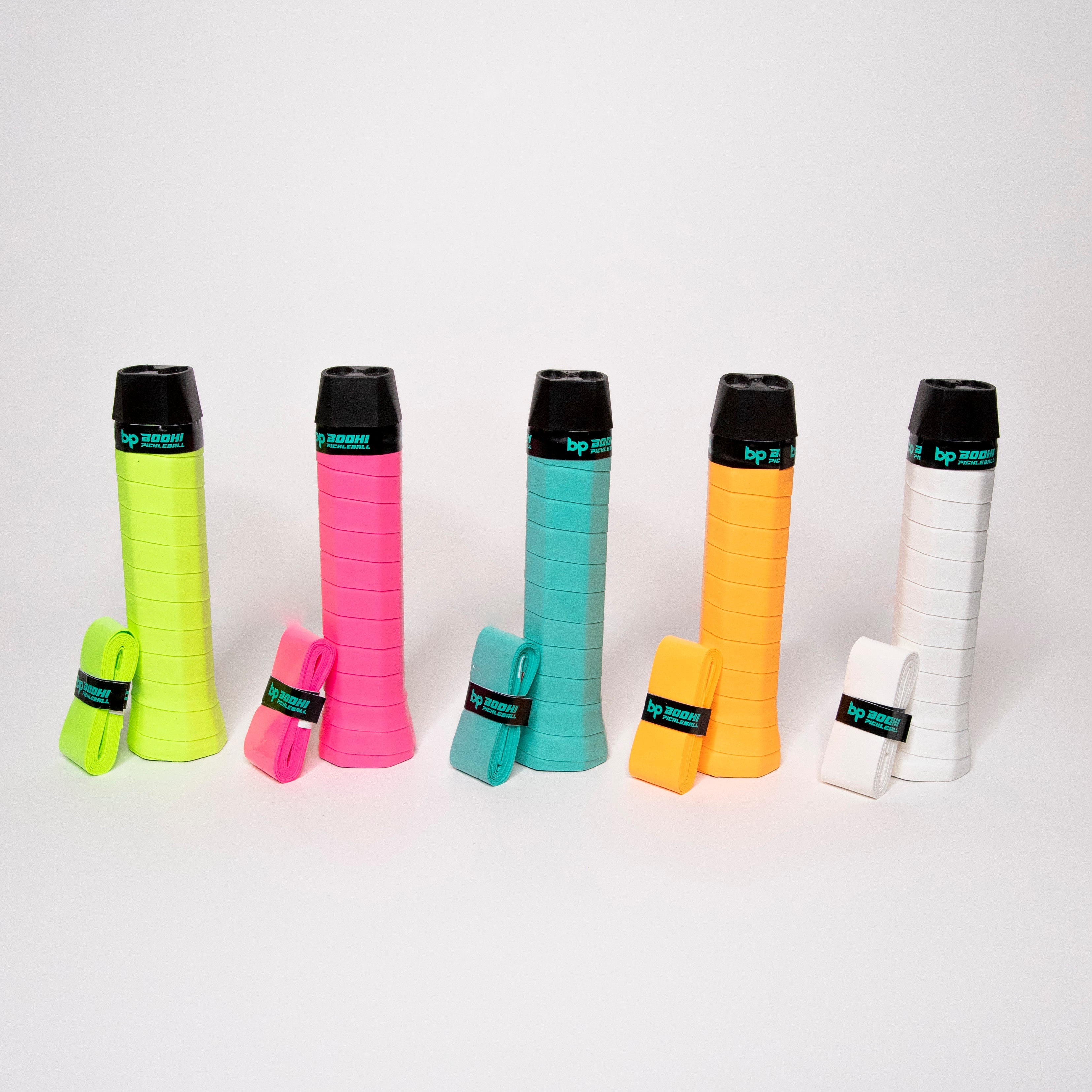 Five colorful pickleball paddle grips with black tops, each with a matching replacement grip, displayed on a white surface.