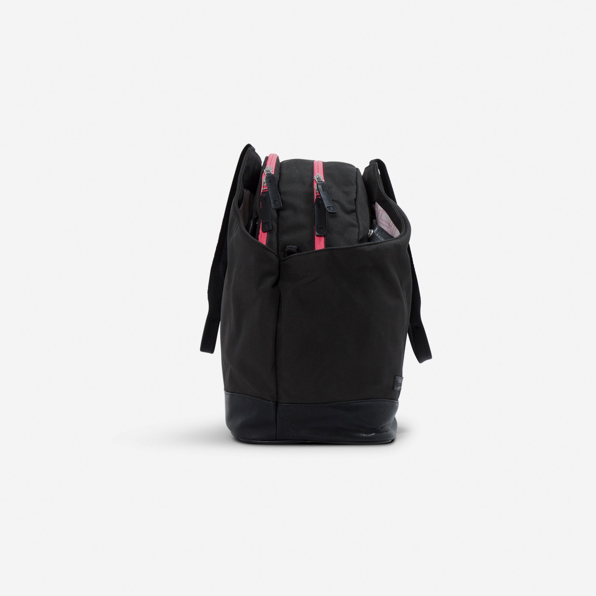 Black tennis duffel tote by Doubletake with bright pink zippers and a black leather base, shown from the side.