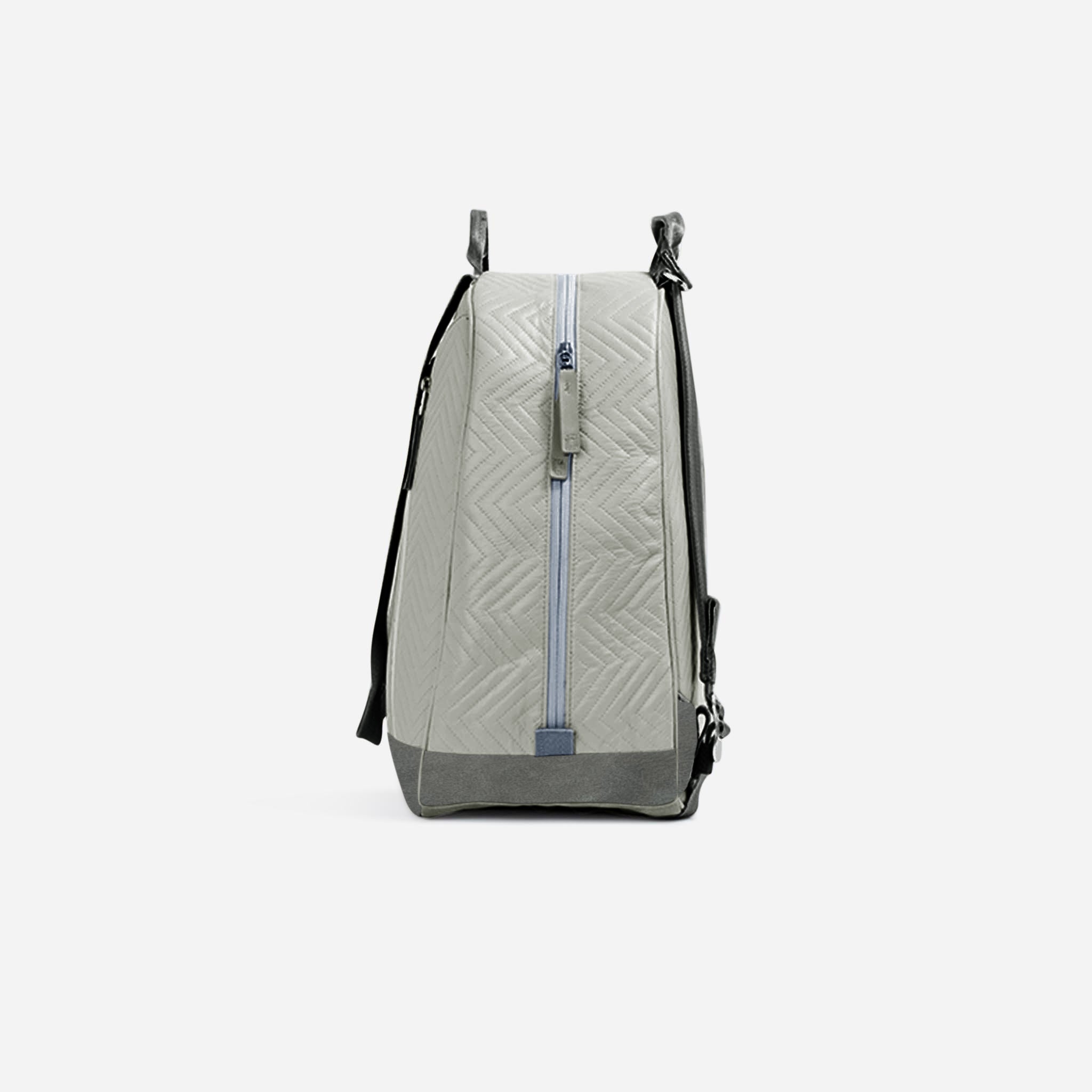 Light grey tennis backpack and tote by Doubletake with a zigzag quilted pattern, dark grey base, and blue side zipper.