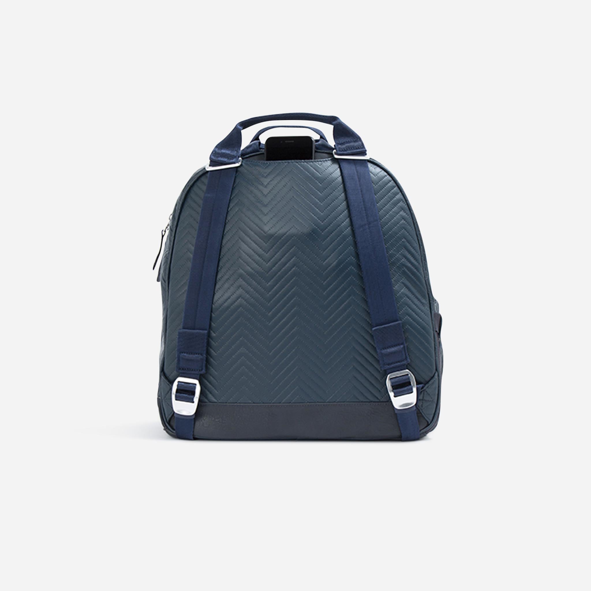 Dark blue backpack by Doubletake with a chevron pattern, adjustable straps, and a phone in the top pocket, back view.