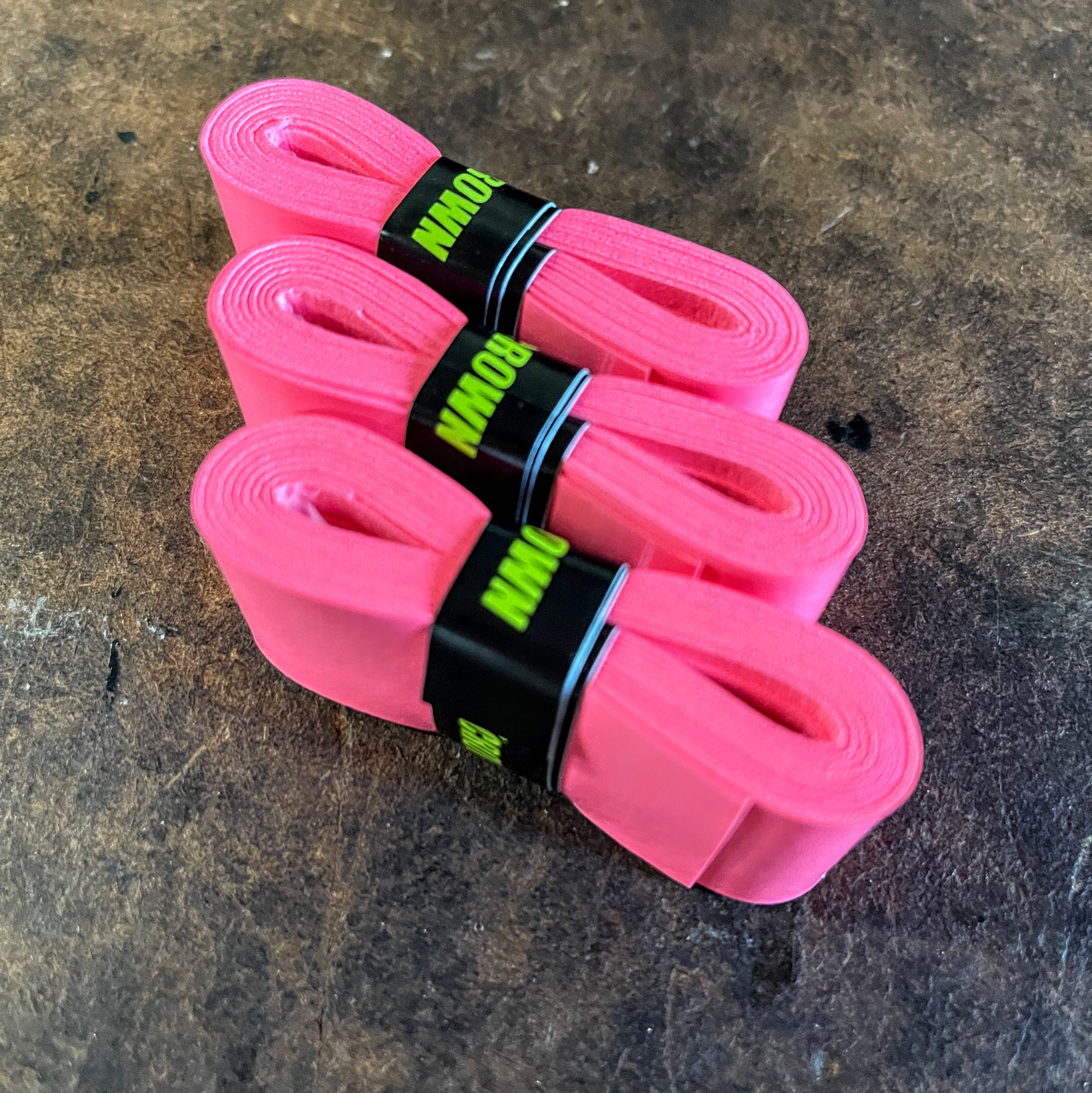 Three rolls of pink athletic tape with black and neon green labels.