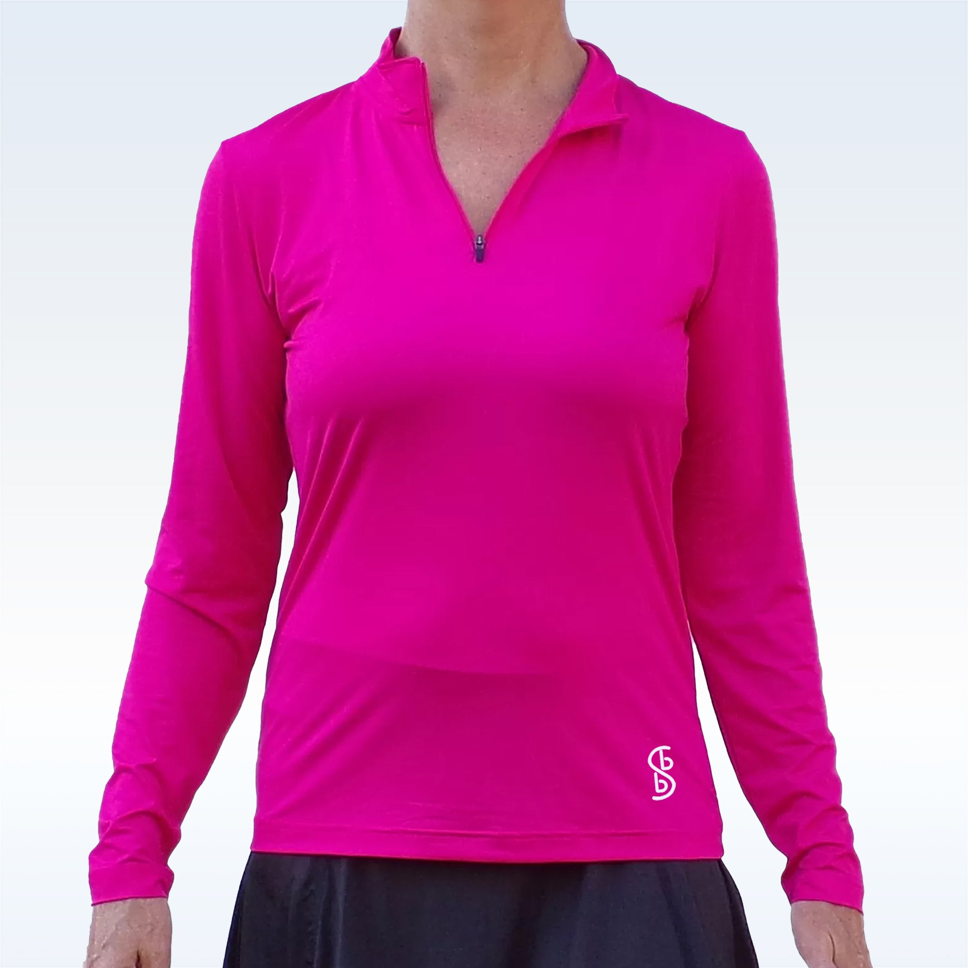 Pink long-sleeve 1/4 zip pullover by Pickleball Bella, featuring a white logo and styled with a black skirt.