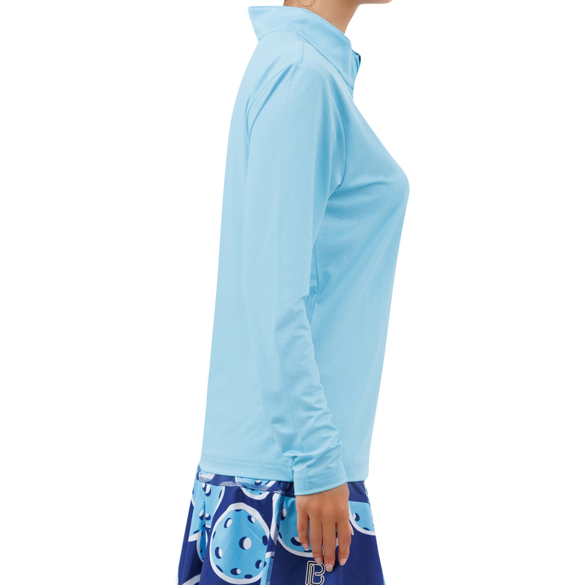 Sky blue 1/4 zip long sleeve pullover by Pickleball Bella, worn by a person from the side with a navy patterned pickleball skirt.