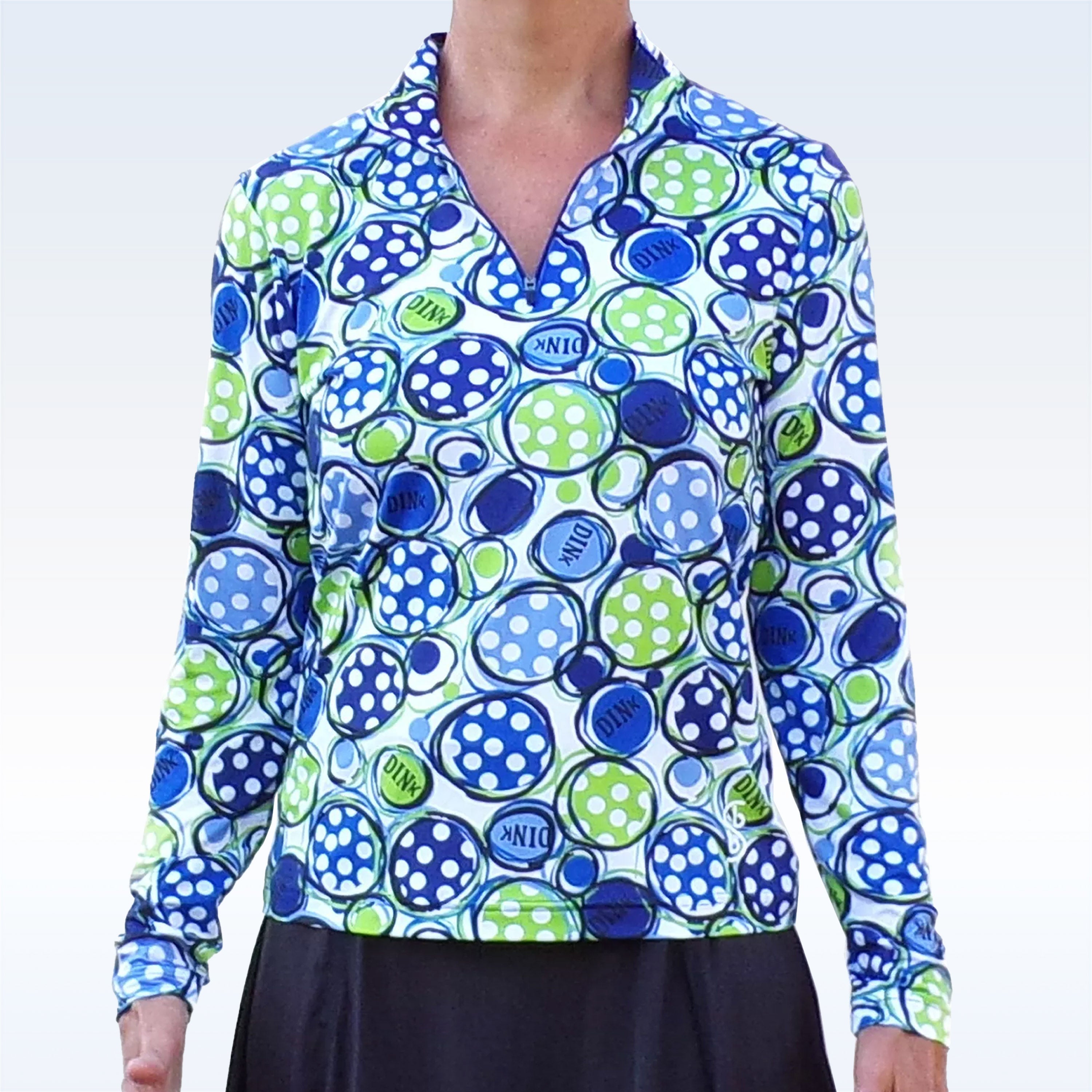Long sleeve 1/4 zip pullover by Pickleball Bella, with blue and green polka-dotted circles and "DINK" text, worn with a black skirt.