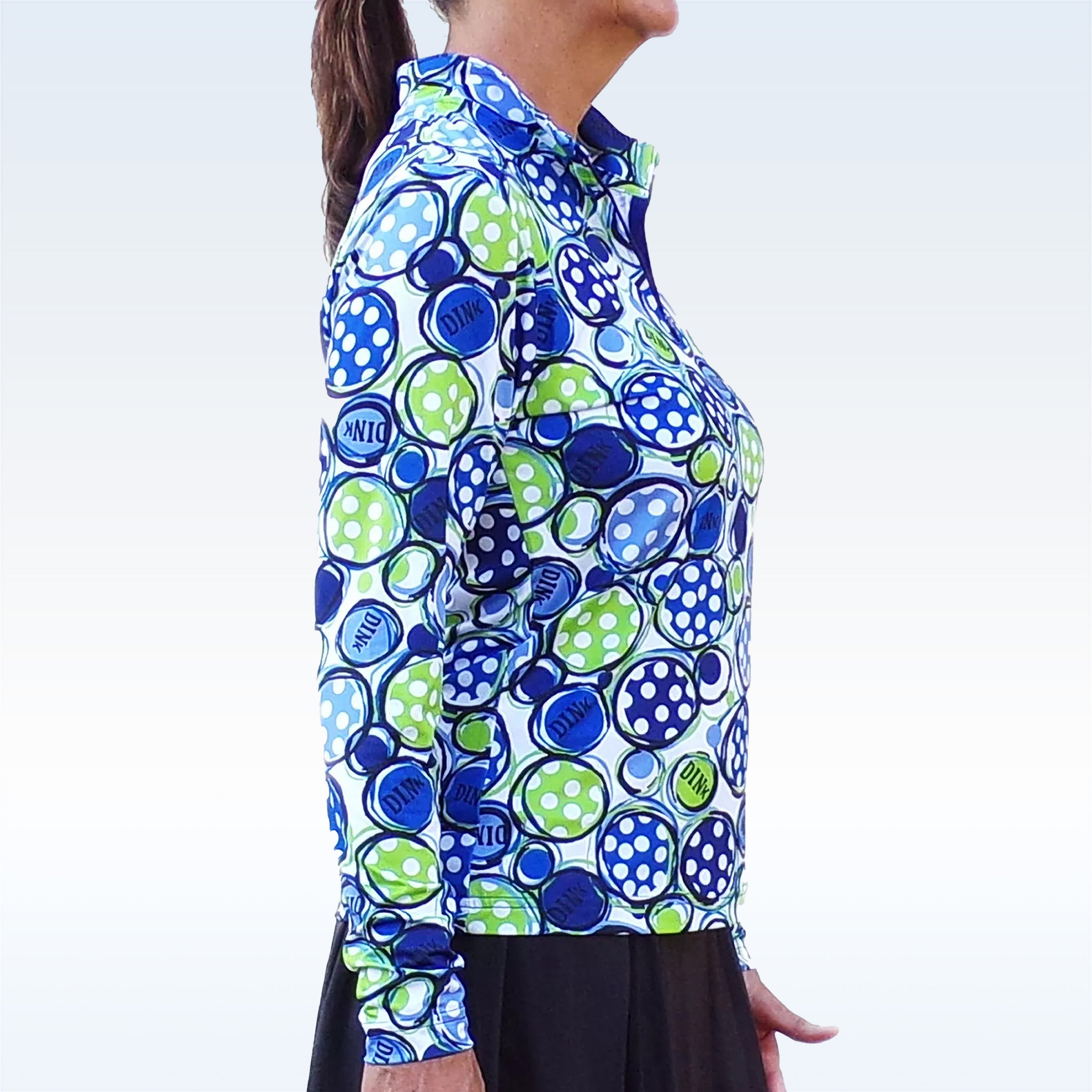 Vibrant blue and lime green 1/4 zip long sleeve pullover by Pickleball Bella, featuring "DINK" and polka dot circles, shown on a woman from the side.