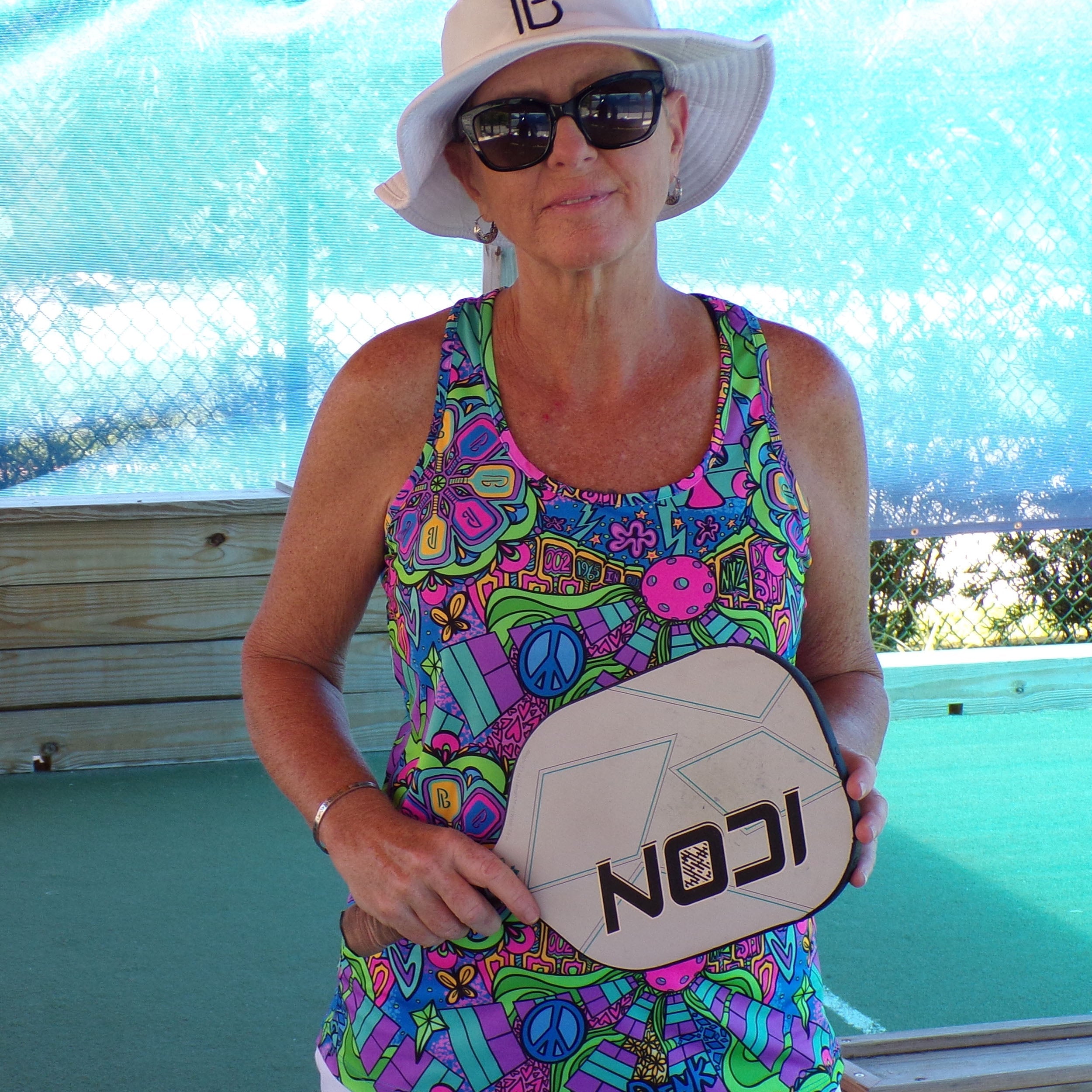 Multi-colored racerback tank by Pickleball Bella featuring a vibrant, psychedelic pattern with peace signs and pickleball paddles.