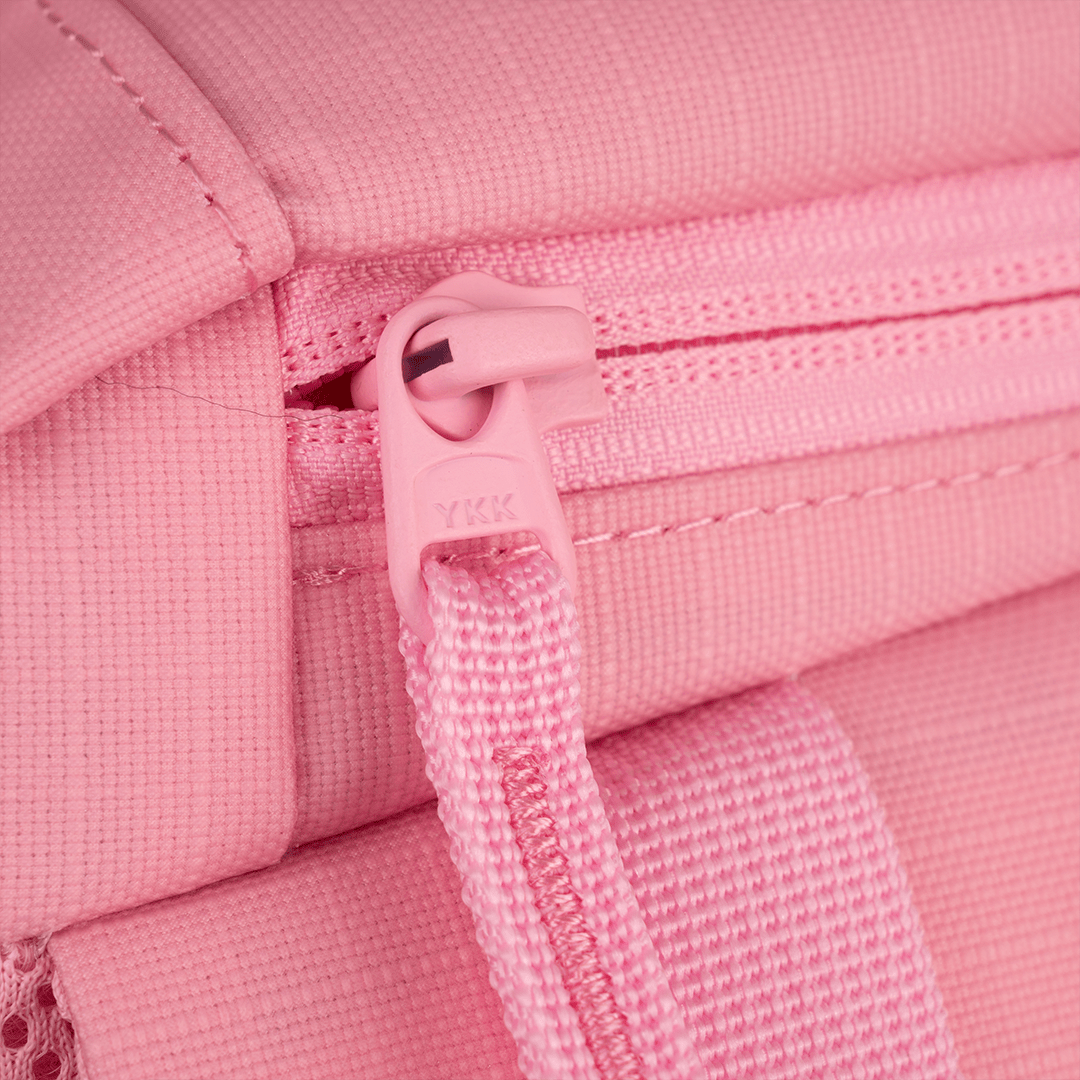 Pink pickleball backpack by FORWRD, close-up of a YKK zipper pull on textured fabric with a woven strap.