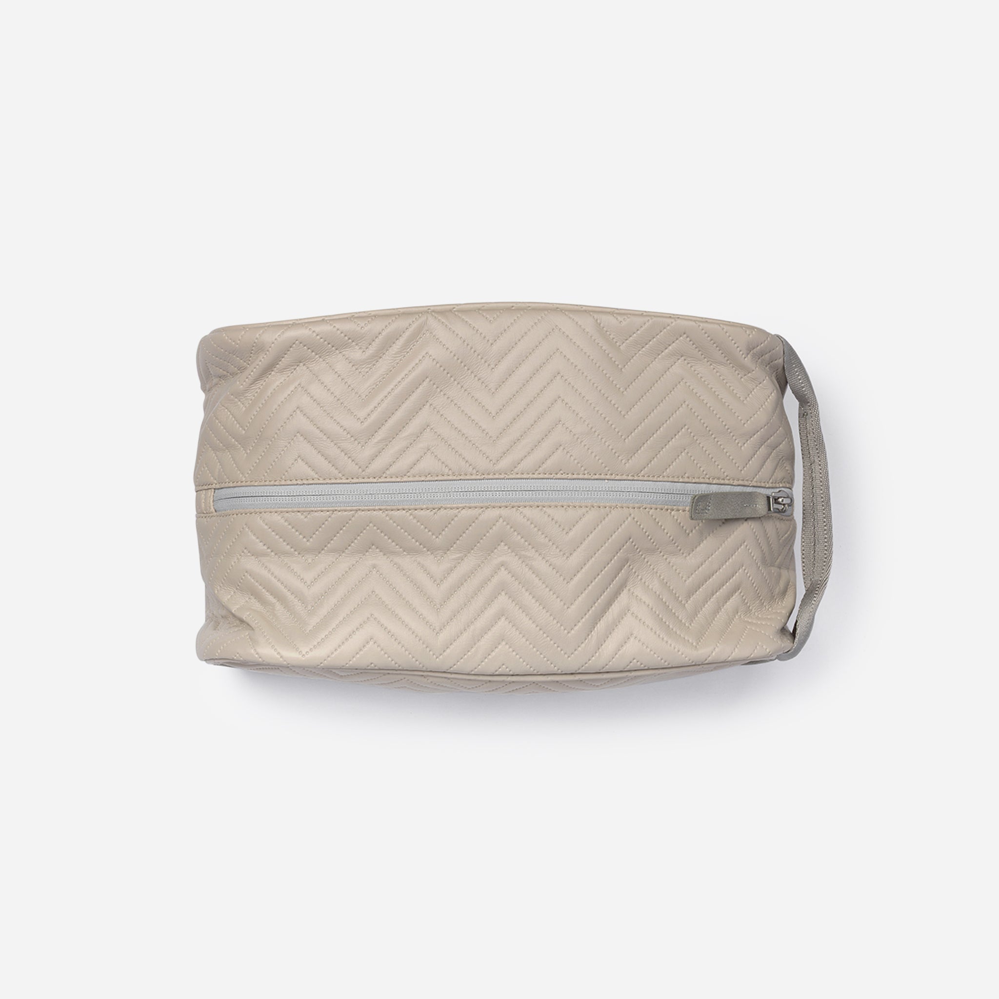 Light beige quilted cosmetic bag with silver zipper and handle.