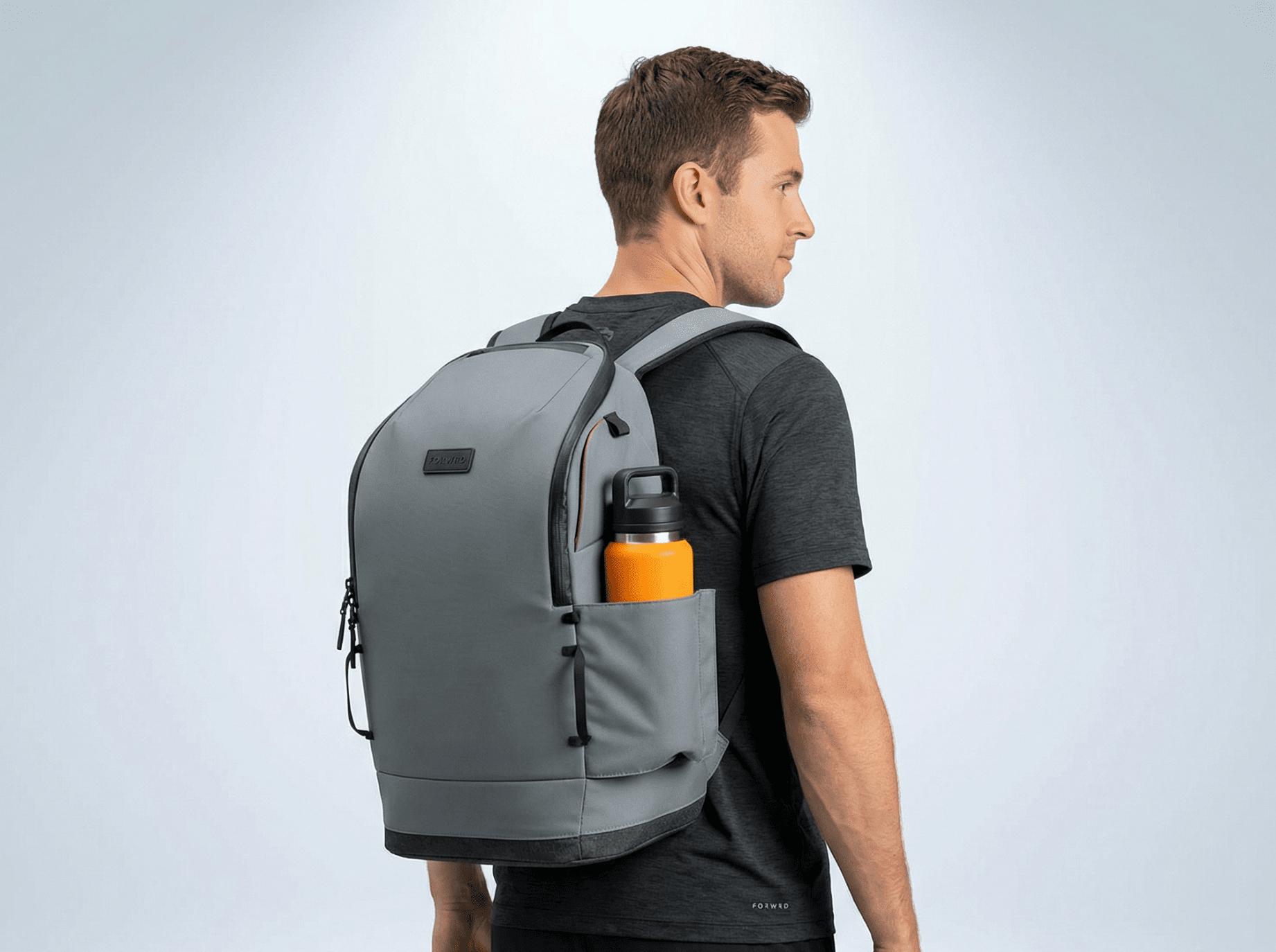 Gray pickleball backpack by FORWRD worn on a man's back, featuring an orange water bottle in its side pocket.