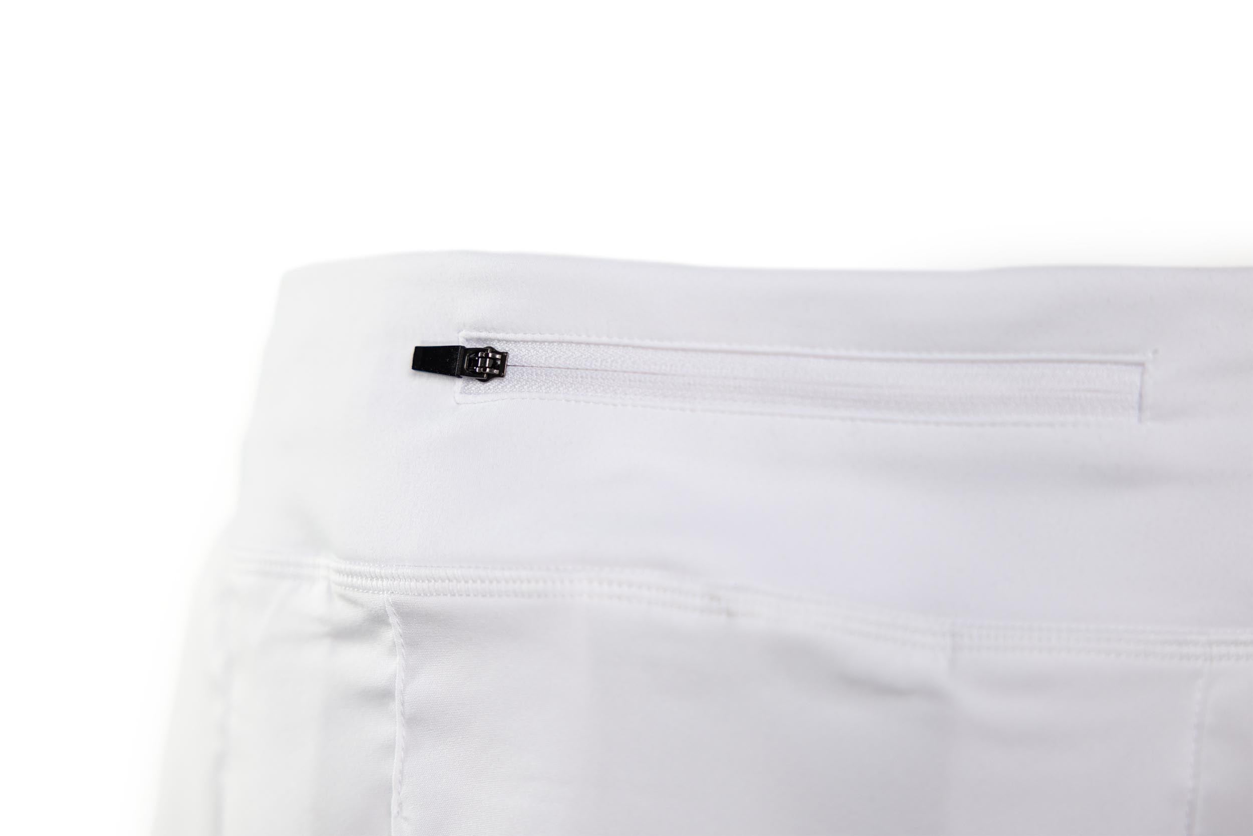 White performance mid-rise skort by TMPR Sports with a back zippered pocket and black zipper pull.
