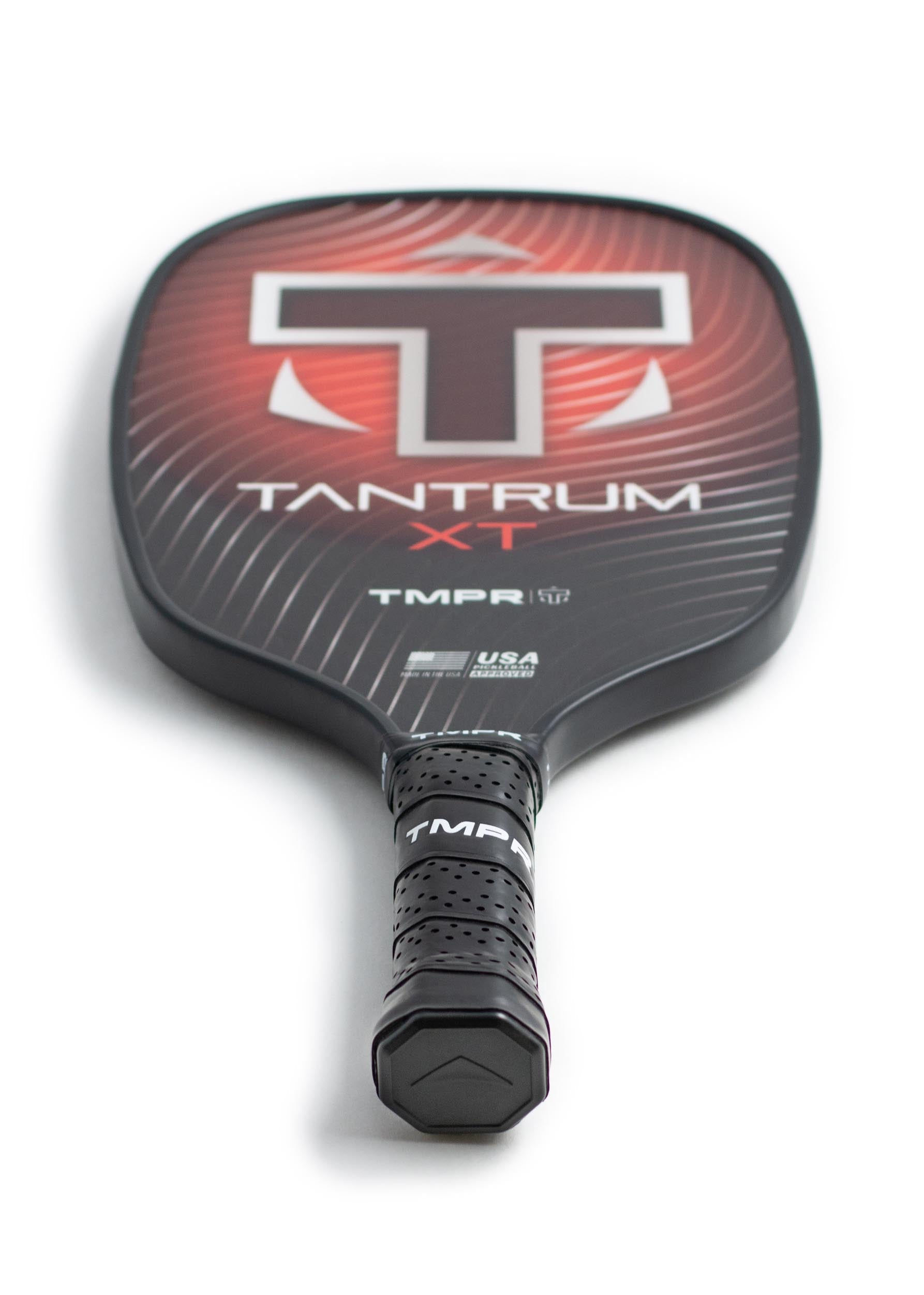 Black and red pickleball paddle by TMPR Sports, featuring a large 'T' logo, linear pattern, and a black perforated grip.