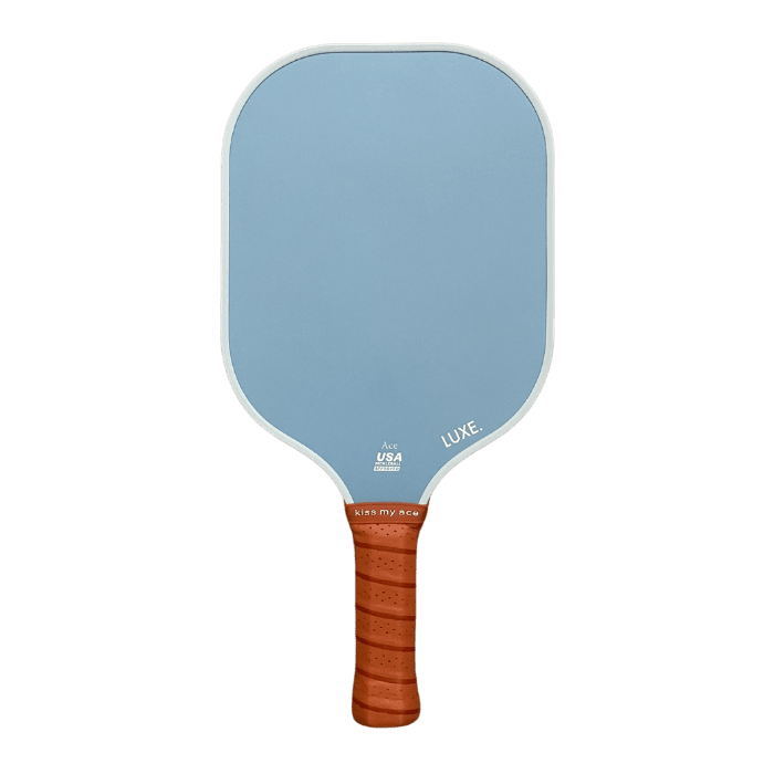 A light blue pickleball paddle with a brown wrapped handle on a green background.