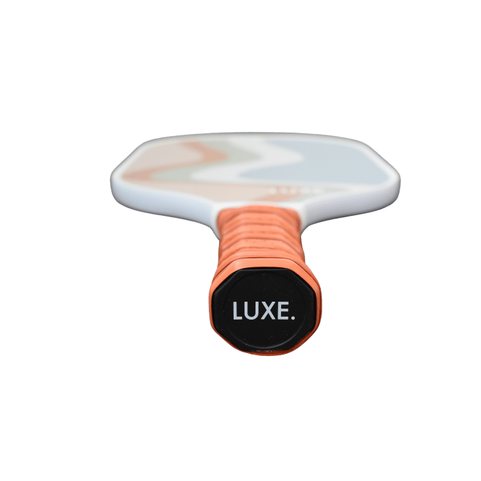 Pickleball paddle with orange grip and "LUXE" text on the handle.
